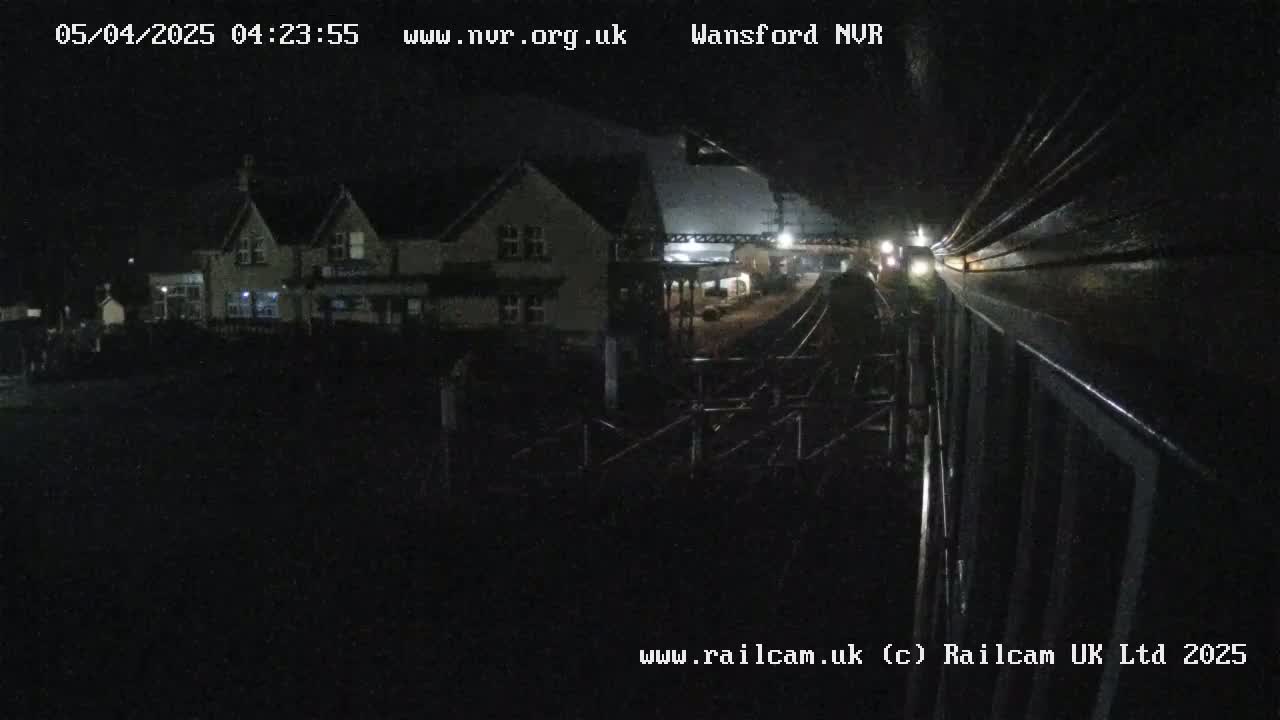 A nighttime view from a train shows a building and railway tracks.
