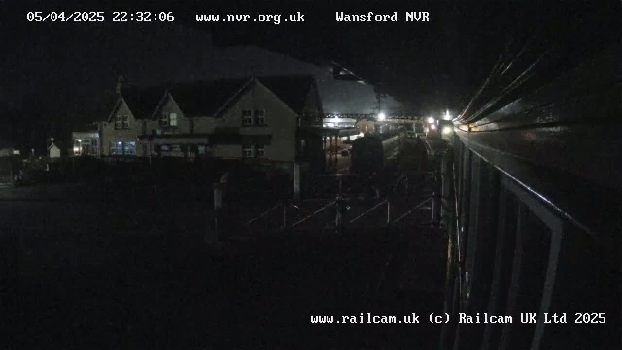 A nighttime view of a building near a train track, under dark, possibly overcast conditions.