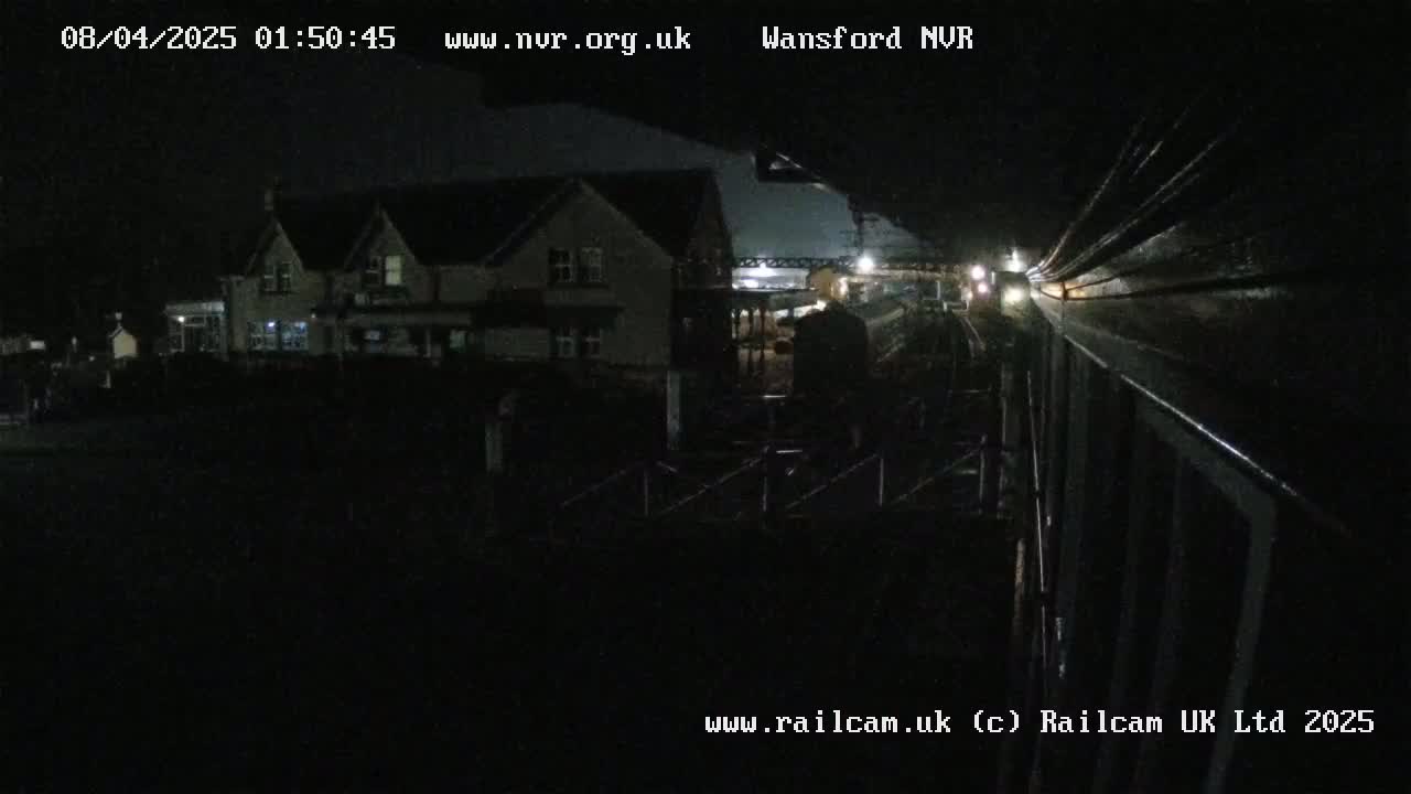 A nighttime view shows a train passing by a building, and the scene is dimly lit.