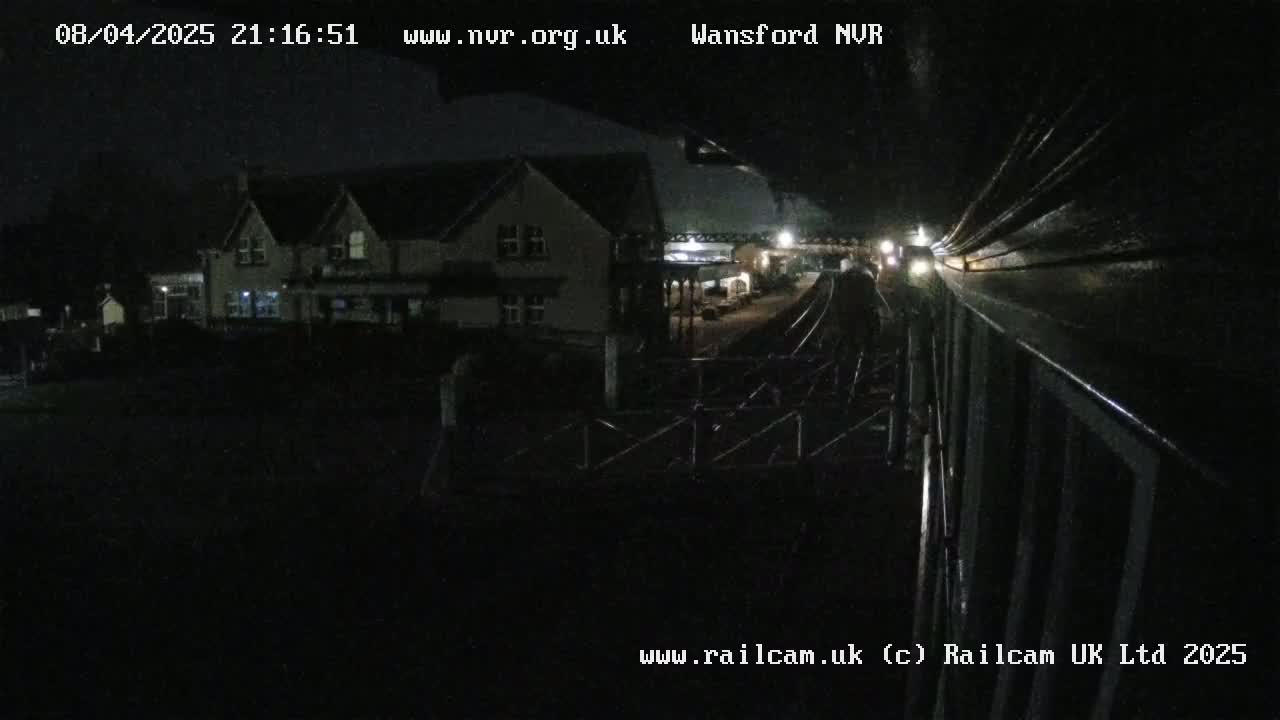 A nighttime view from a train shows a building and railway tracks.