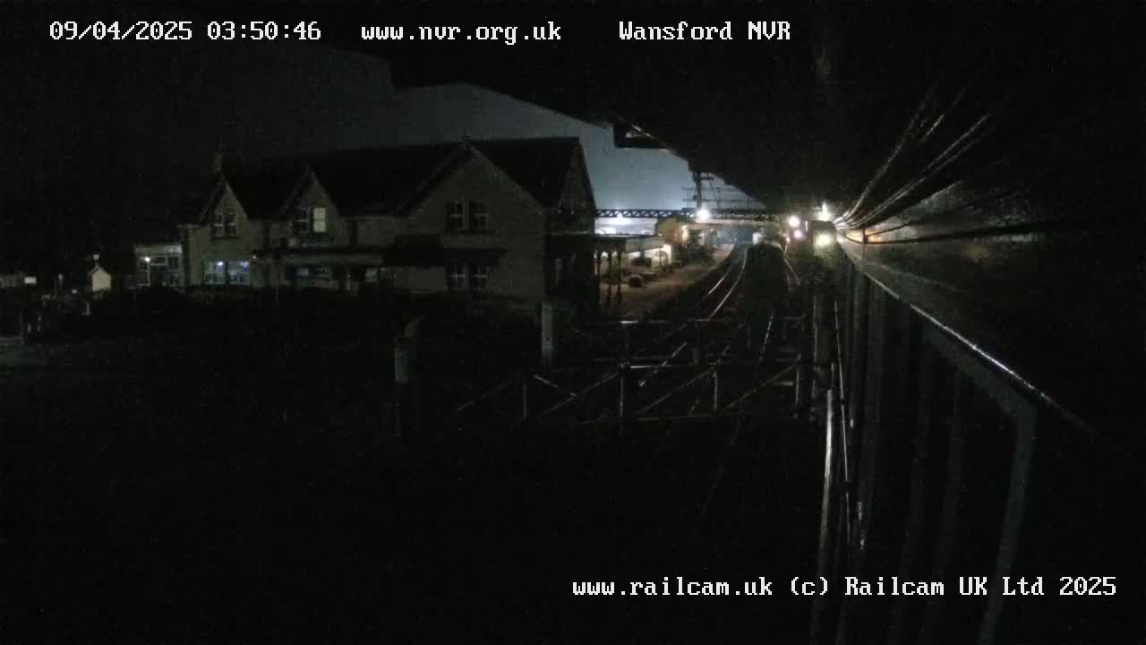 A nighttime view from a train shows a building and train tracks in the distance.
