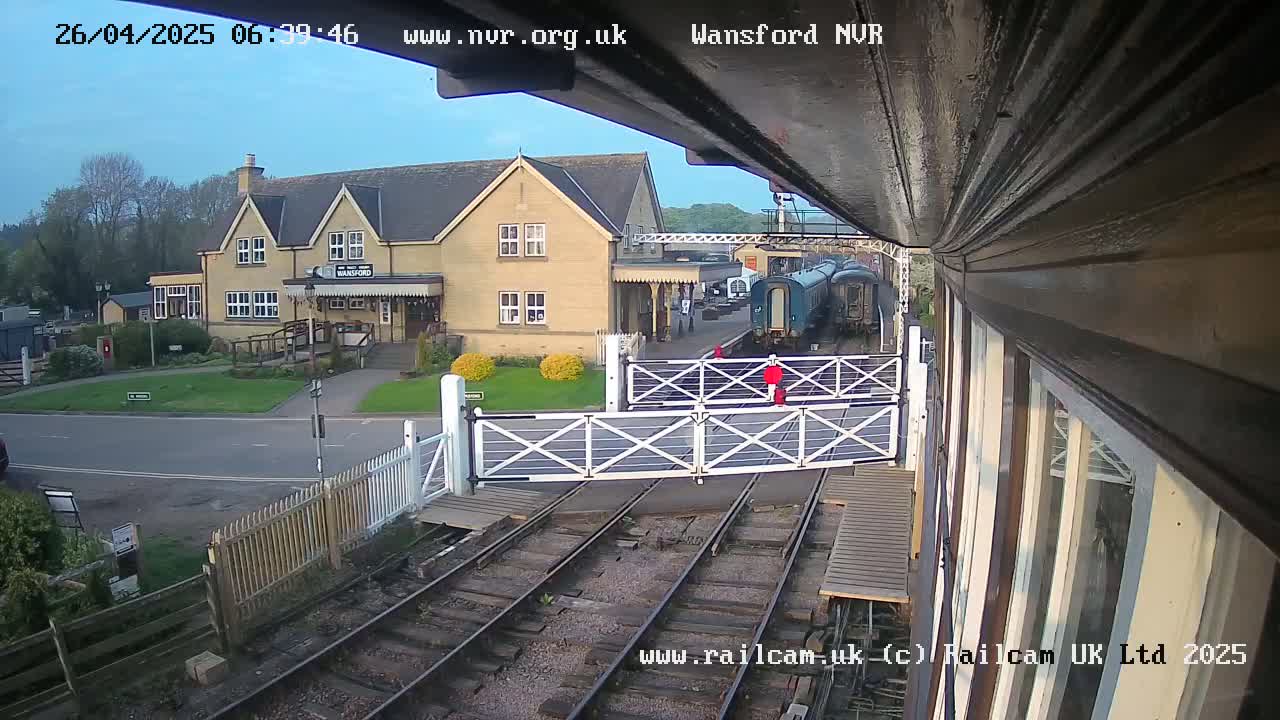 A train is stopped at a station next to a building, under a partly cloudy sky.