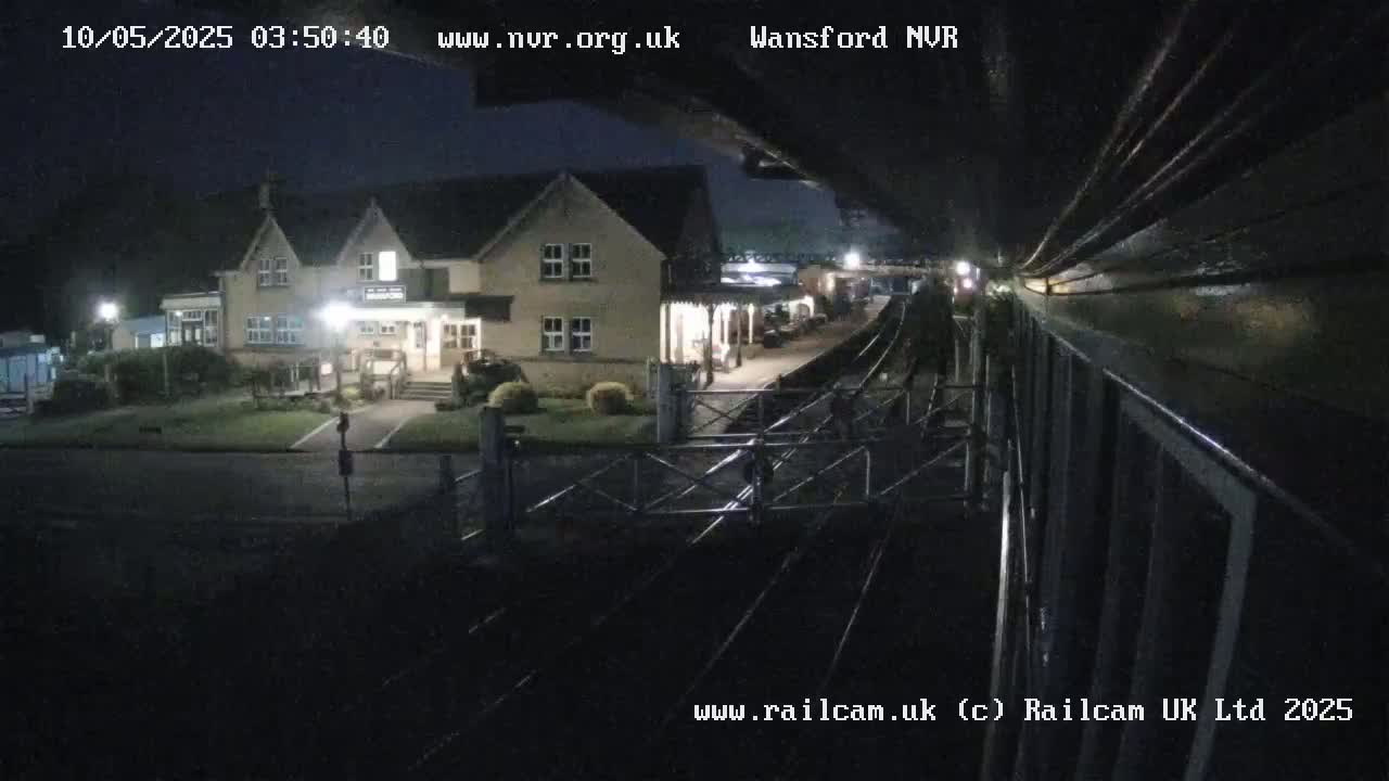 A nighttime view from a train shows a building and railway tracks.