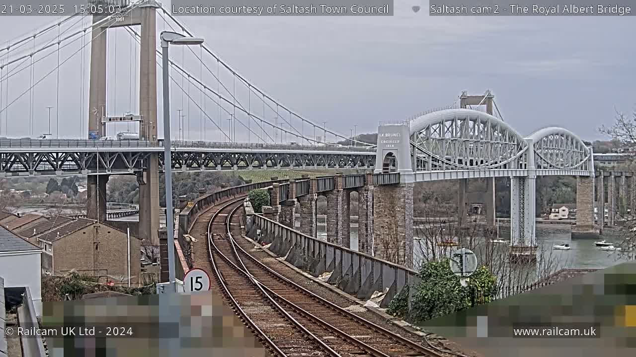 A view of train tracks leading to two bridges over a body of water on an overcast day.
