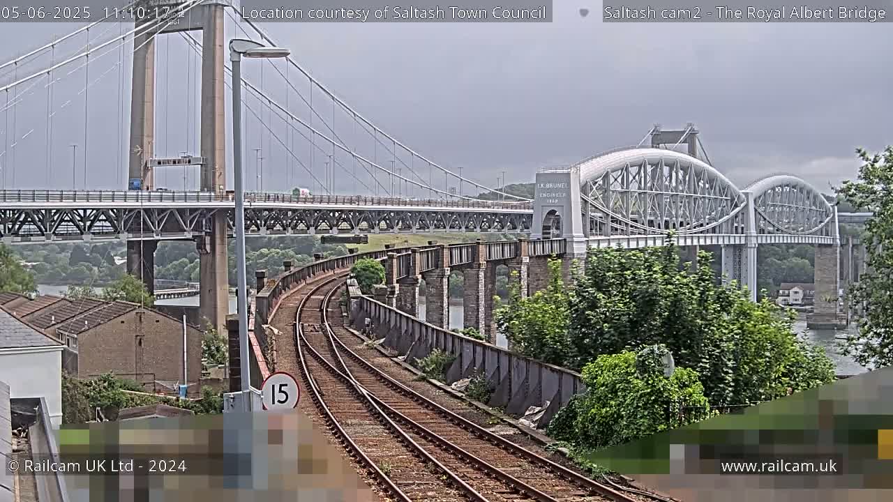 Train tracks curve toward two bridges on an overcast day.