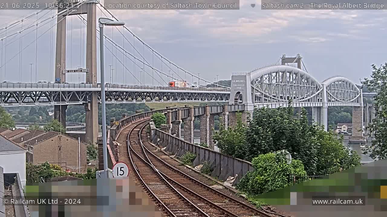 Train tracks curve toward a view of two bridges on an overcast day.