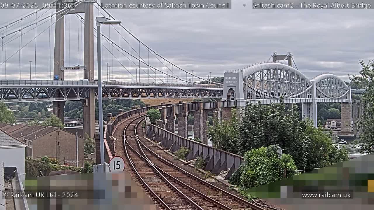 A railway line curves towards two bridges spanning a waterway under an overcast sky.