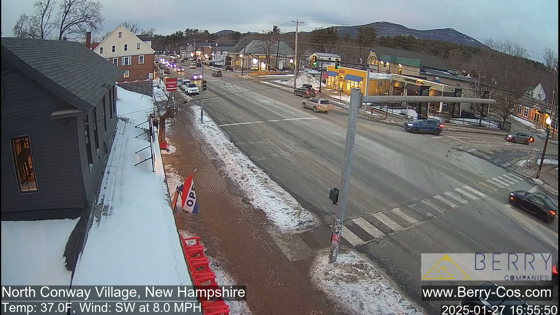 A street scene in a village with snow on the ground and light traffic under a cloudy sky.