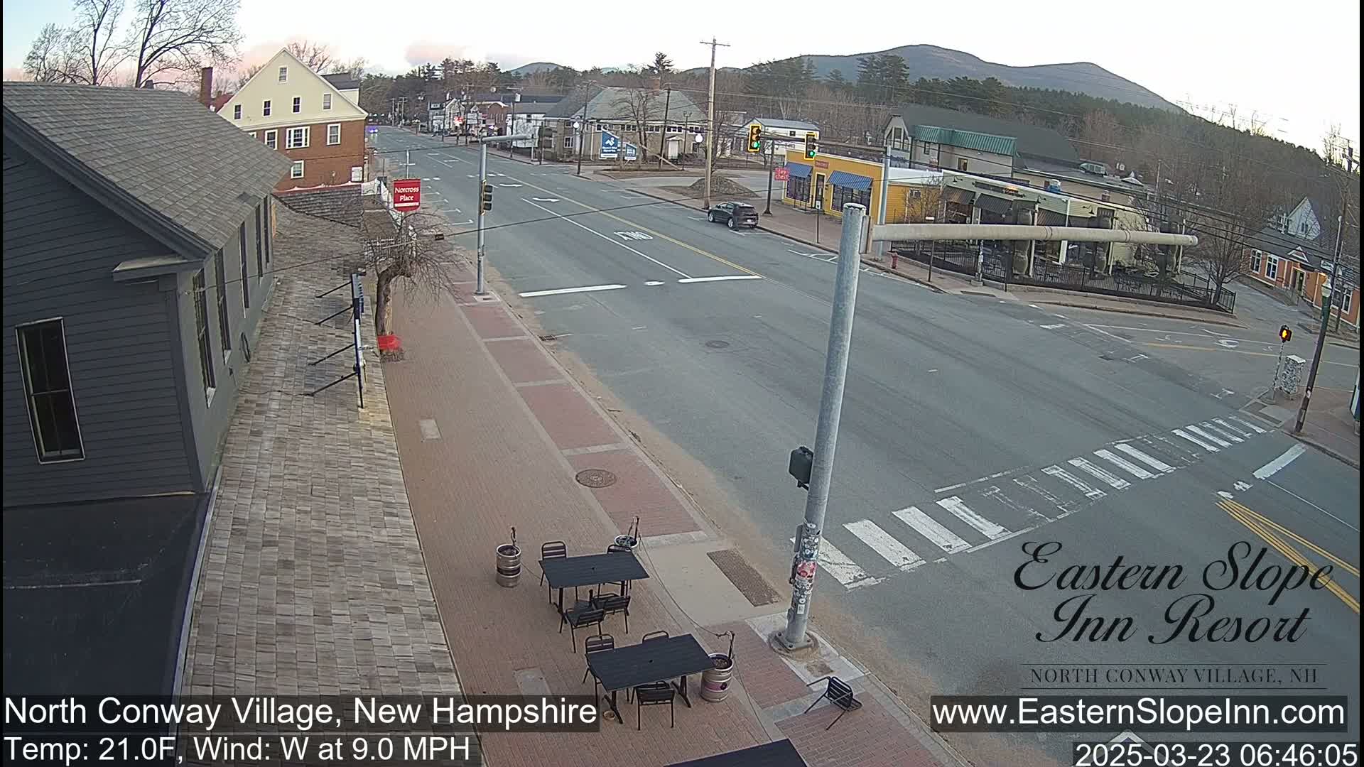 A mostly empty street scene in a small town on a clear, cool morning, with a few cars and buildings visible.