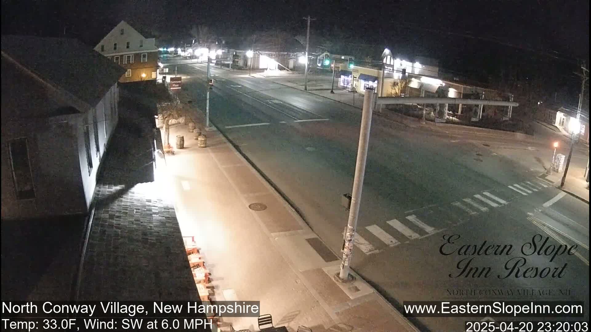 A nighttime view of a mostly empty street intersection in a small town, with a southwest wind at 6 mph and a temperature of 33 degrees Fahrenheit.