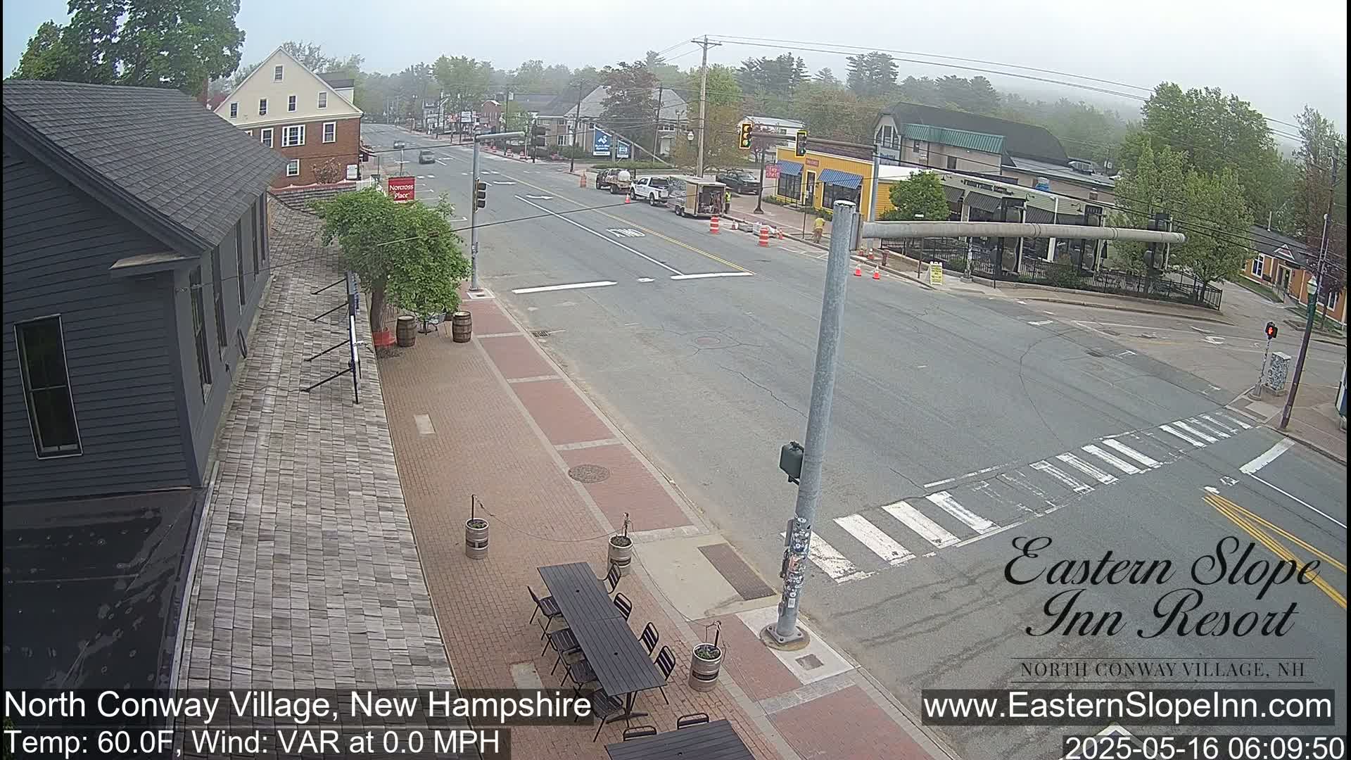 A mostly clear, street-level view shows a street intersection with several buildings and some outdoor seating.
