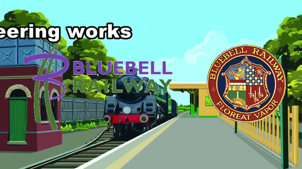 A steam train sits at a station platform on a sunny day, next to a water tower and a wooden fence.