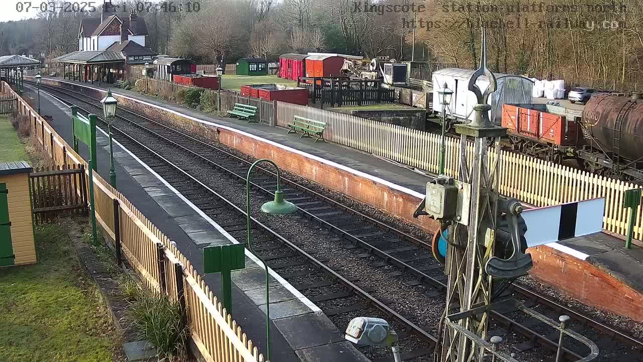 A train station platform with several railway cars and a building on a sunny day.