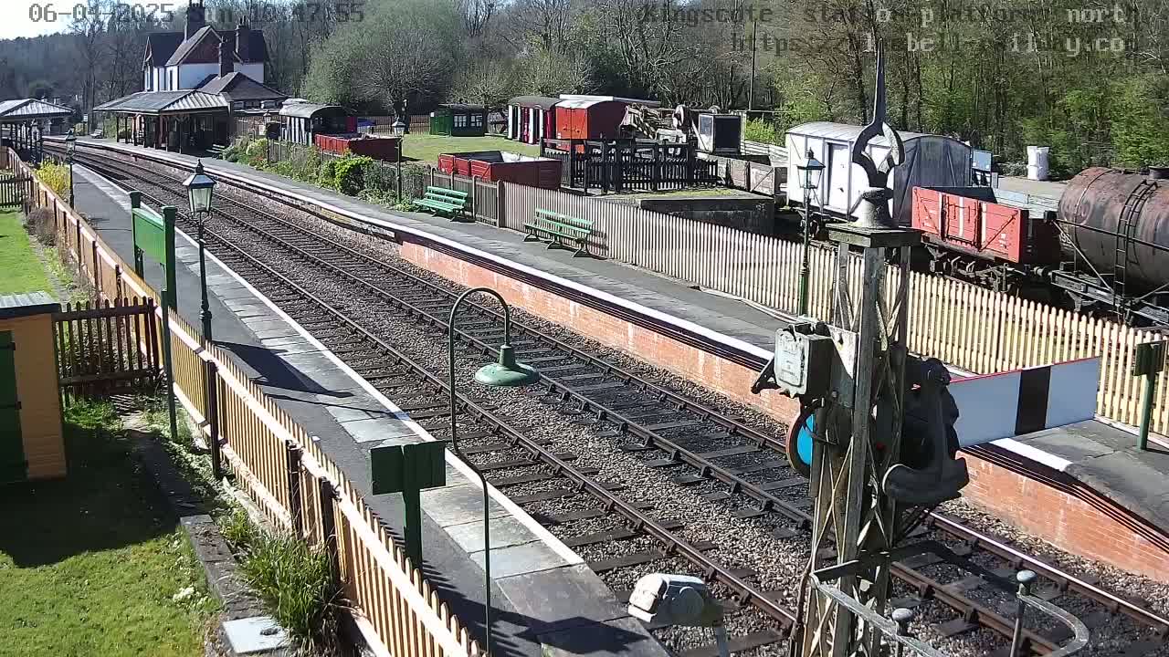 A sunny day at a railway station with multiple train cars and tracks, some of which are empty.