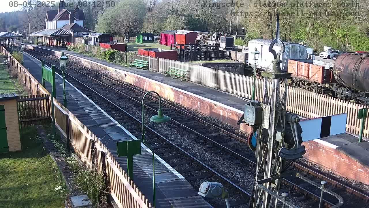 A train station platform with multiple train cars and a sunny day.