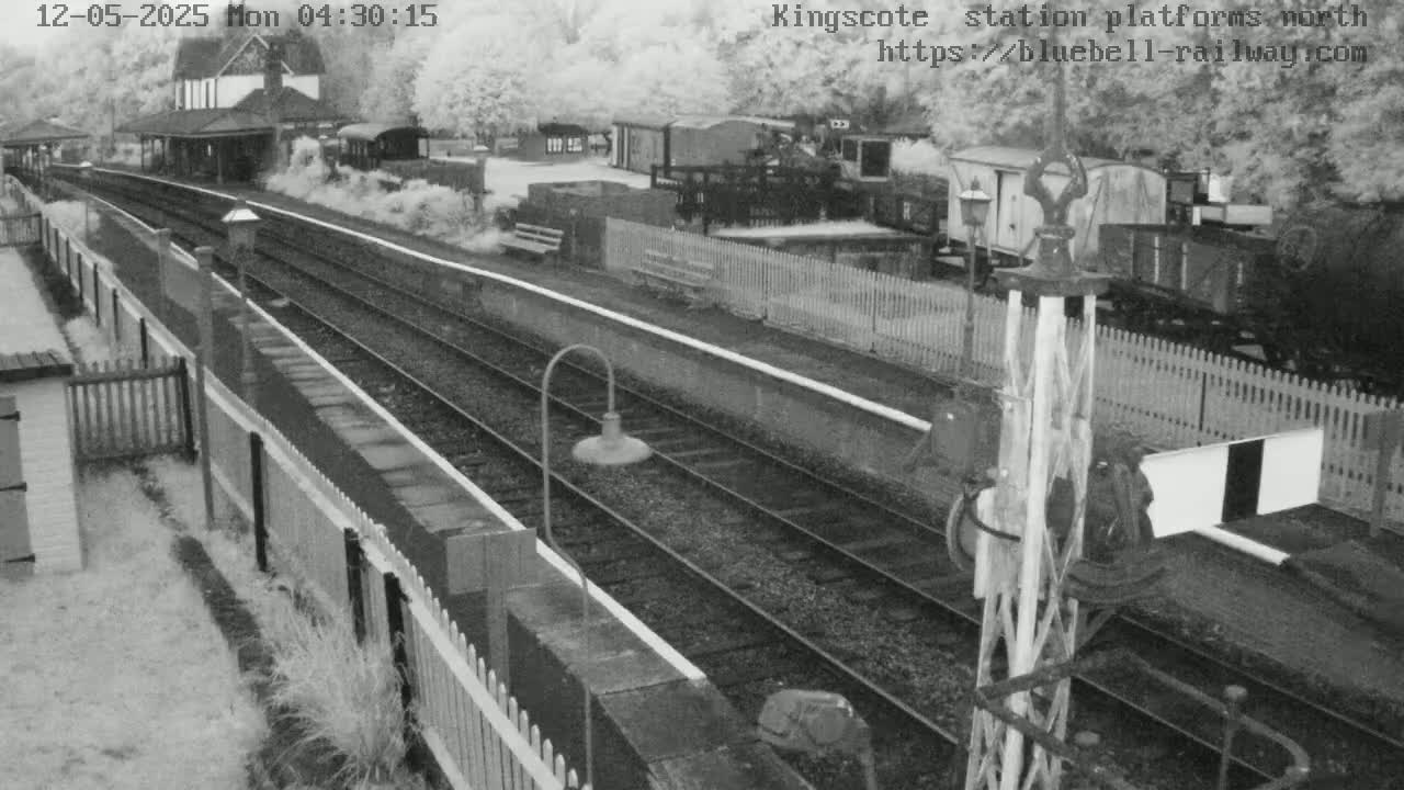 A high-angle view of a train station platform with railway tracks and various railway equipment, under overcast skies.