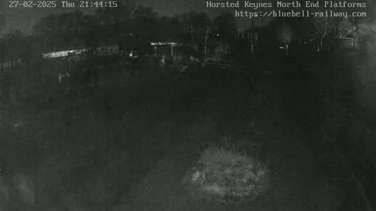 A nighttime, low-light view shows a dark, mostly empty area with some indistinct structures in the distance.