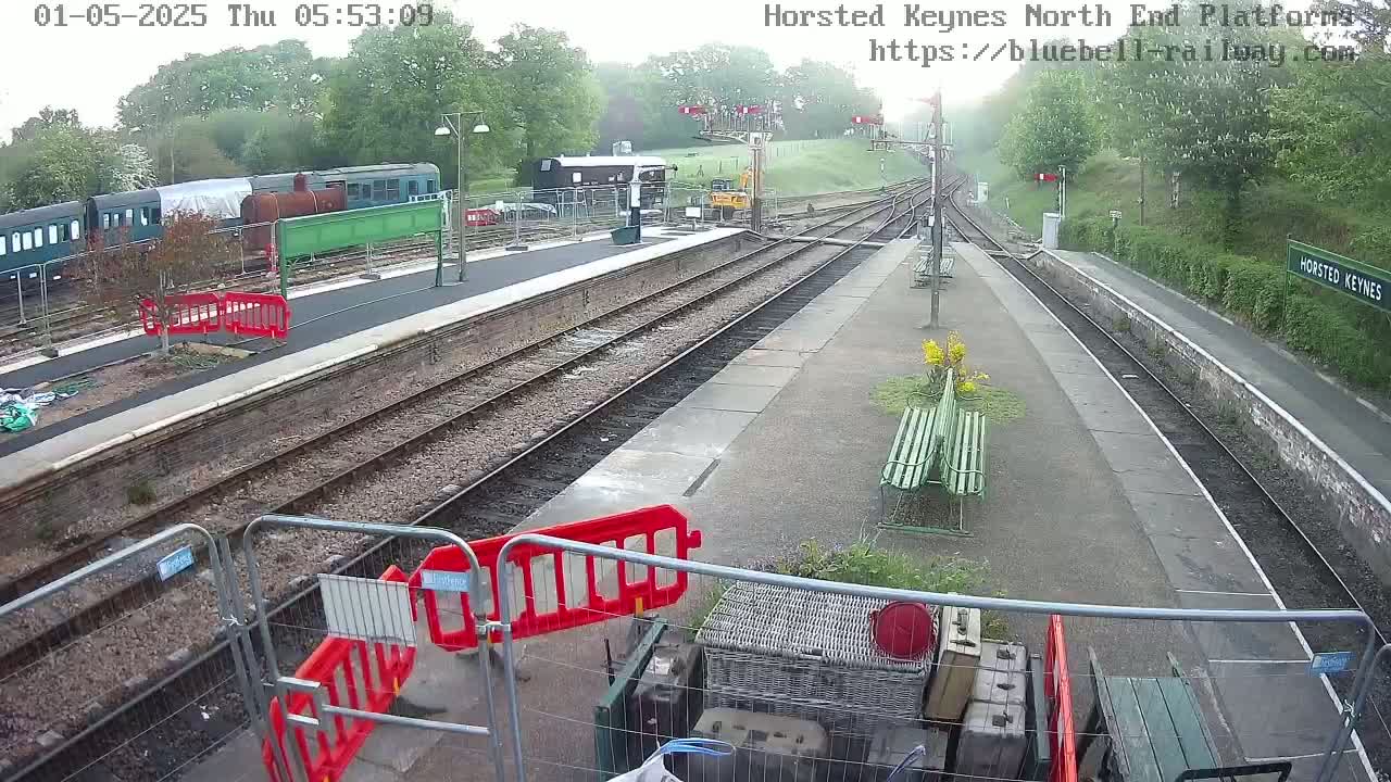 A railway station platform with several train cars parked nearby on an overcast day.