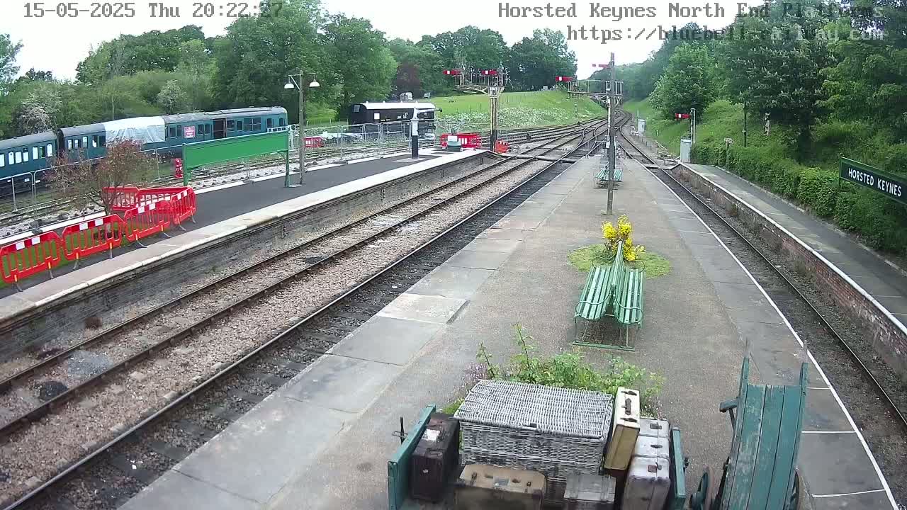 A train station platform with several train cars, some of which are covered, under a mostly clear evening sky.