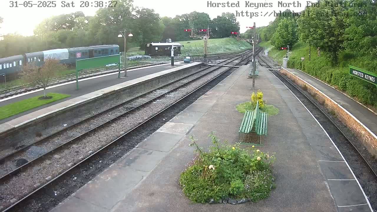 A train sits at a mostly empty railway station on a partly cloudy evening.