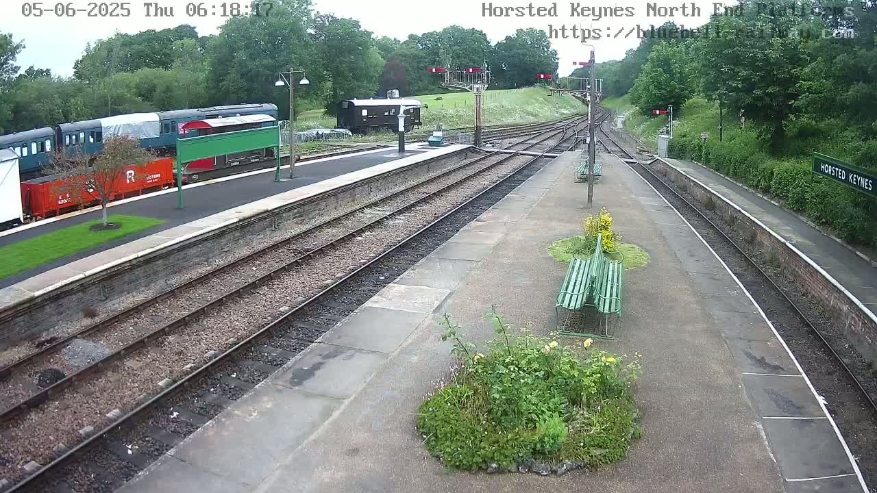 A mostly empty train station with several rail cars parked on the tracks, under an overcast sky.