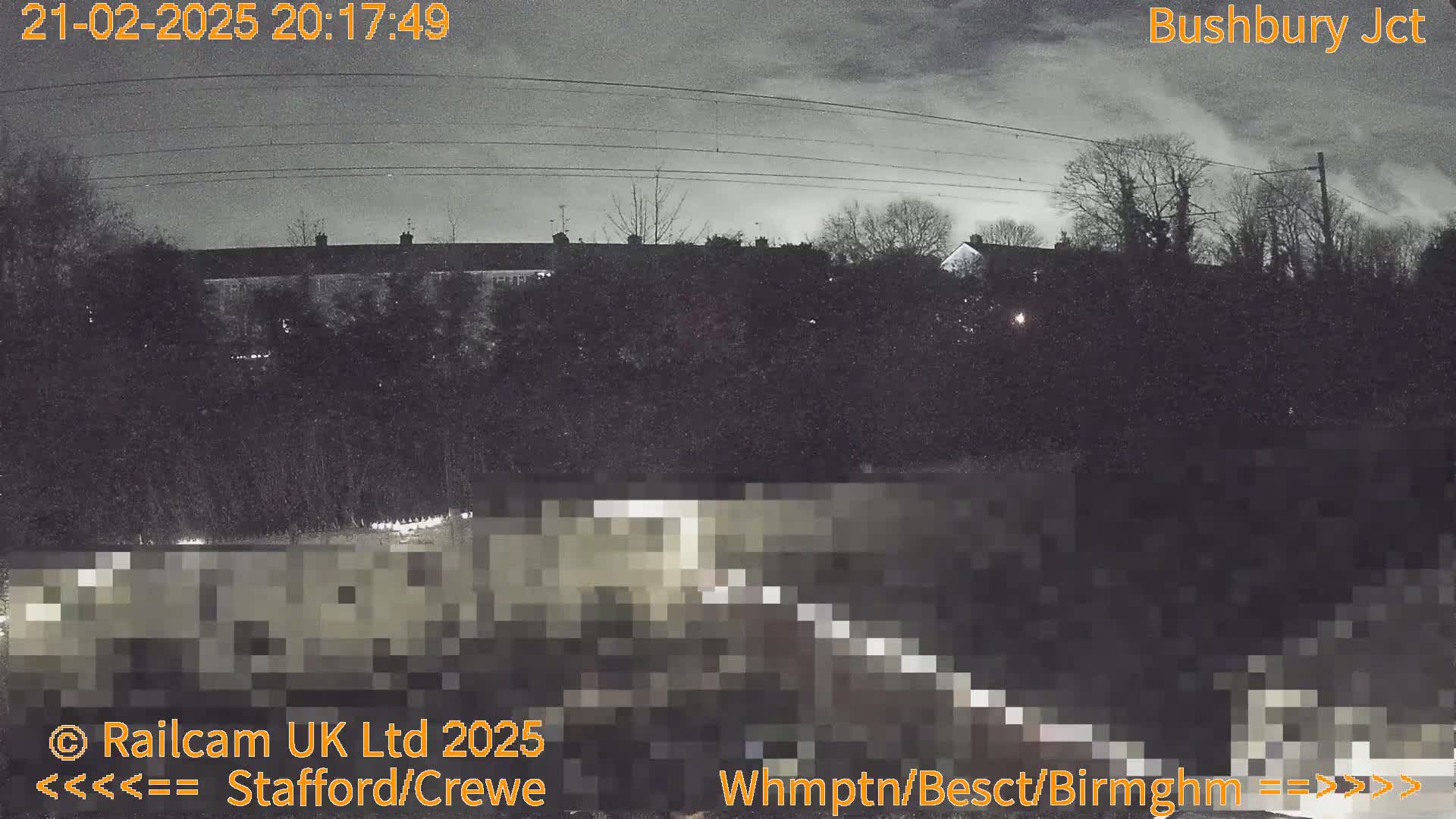 A nighttime view of houses and trees under a cloudy sky.