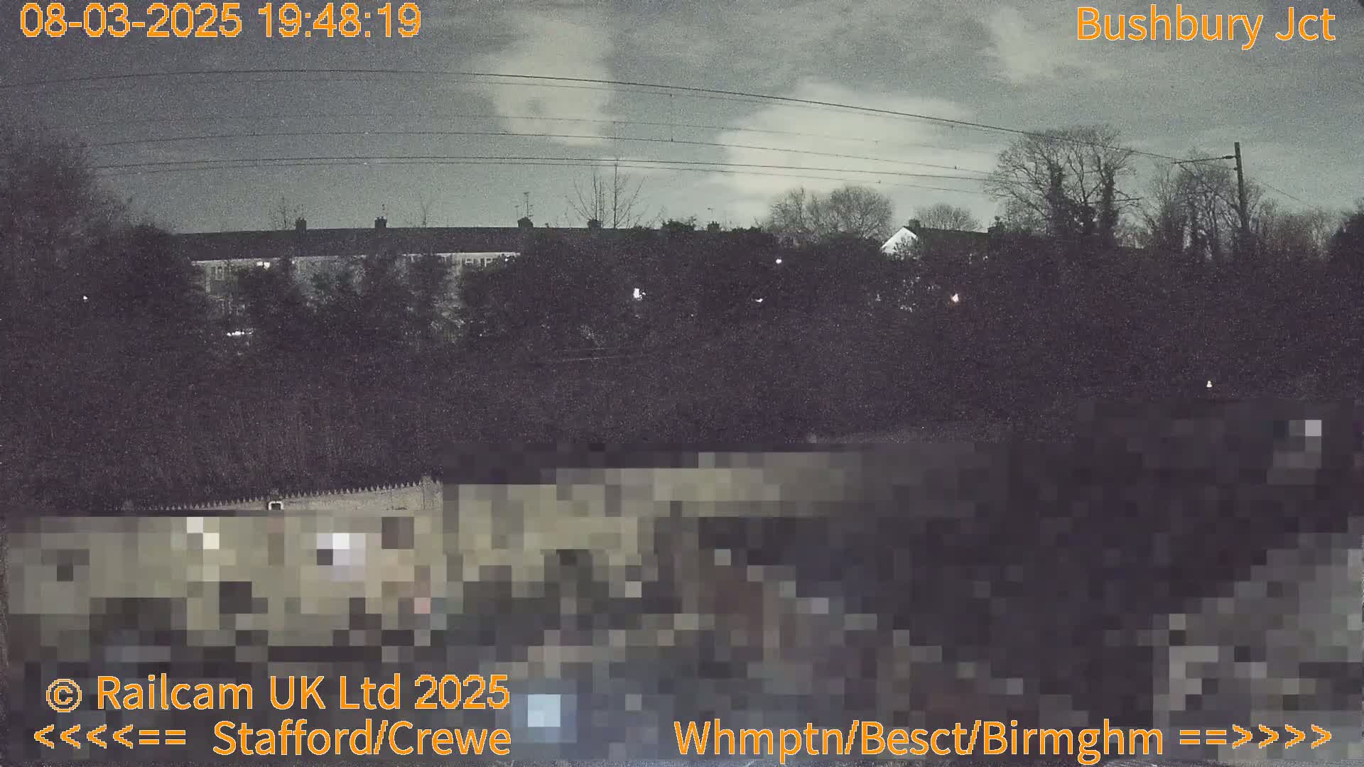 A nighttime view of a residential area with trees and buildings under a cloudy sky.