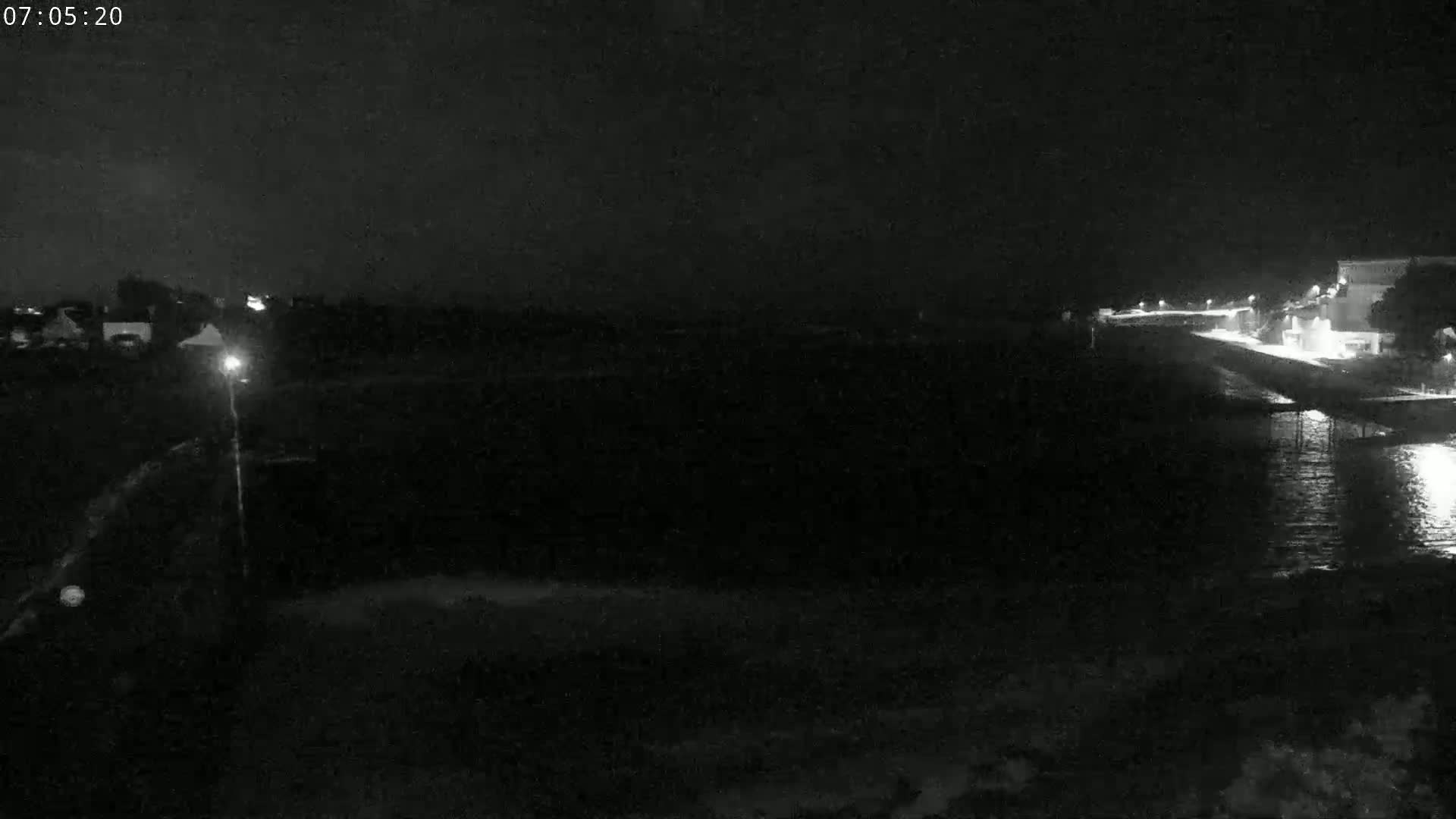 A nighttime, low-light view of a dark body of water next to a dimly lit shoreline.