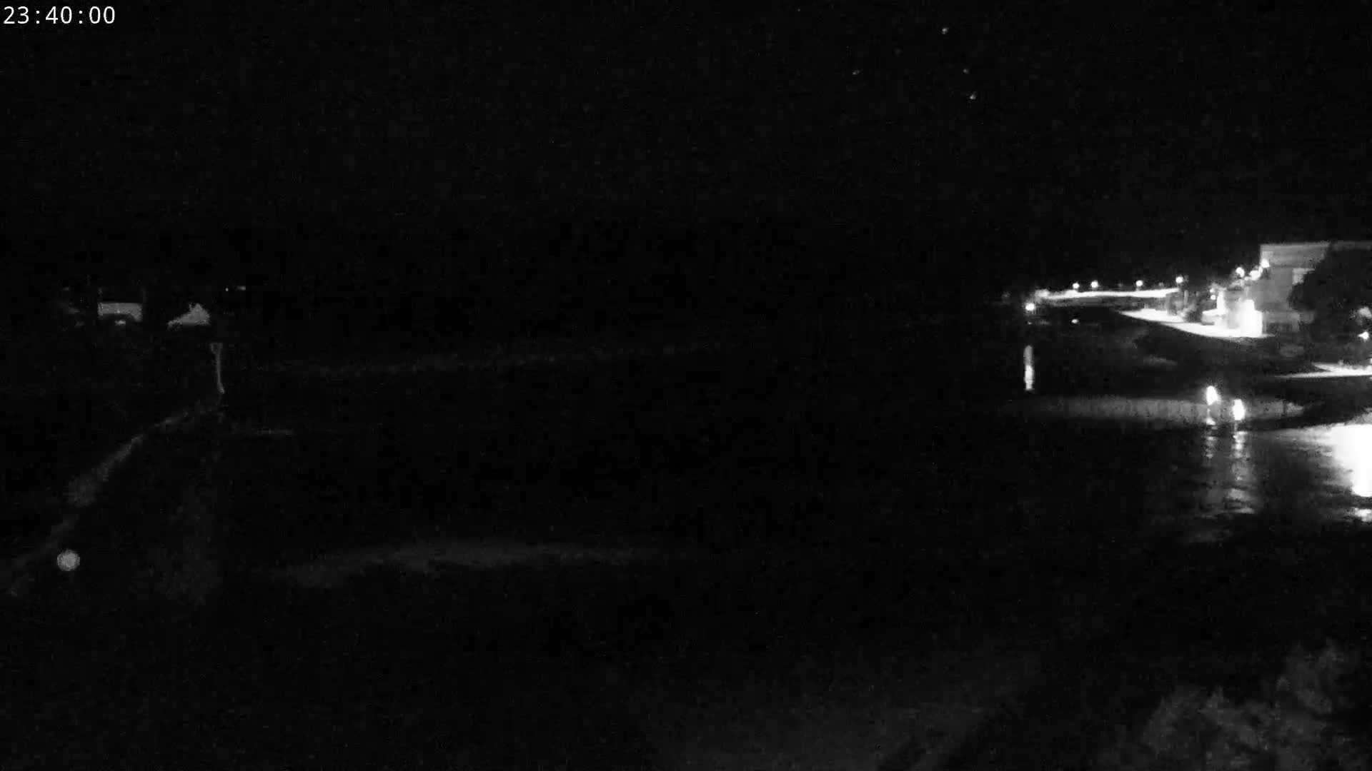 A nighttime view of a dark body of water next to a dimly lit shoreline.