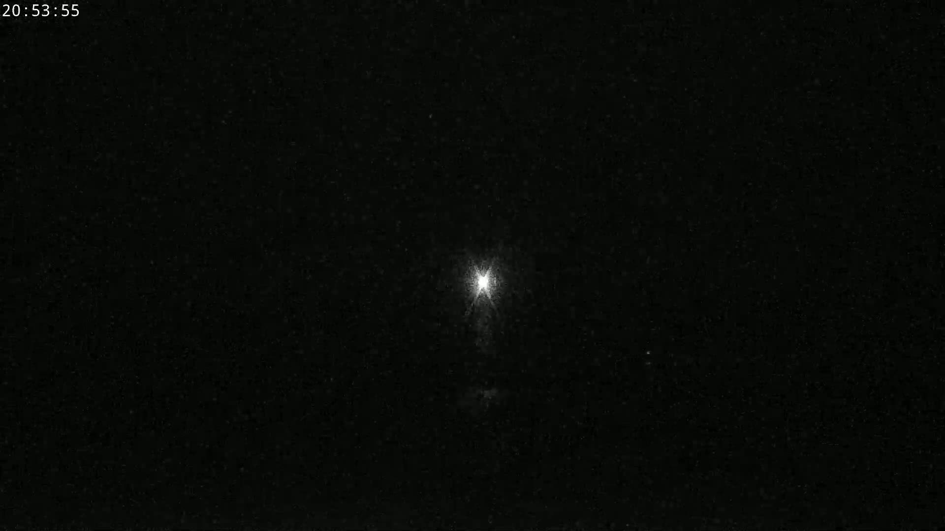 A bright light shines in the center of a dark, nighttime sky.