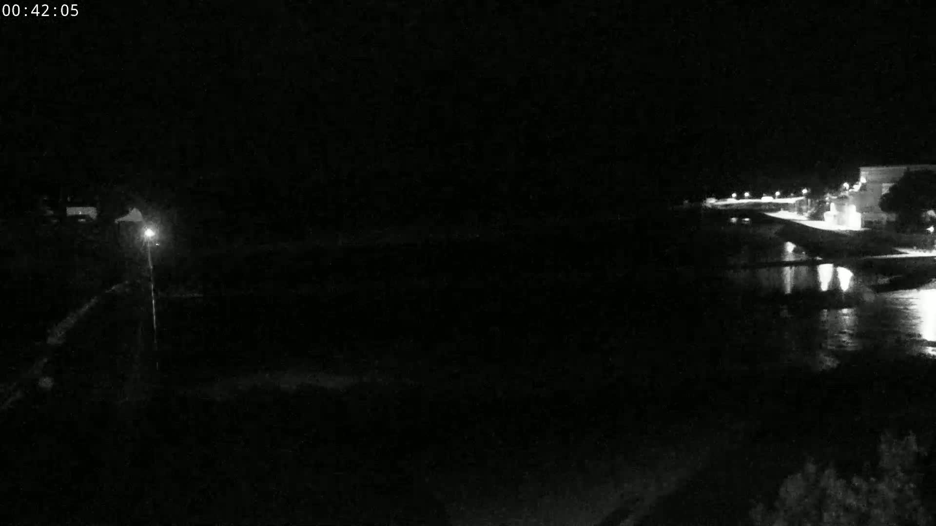 A nighttime, low-light view of a body of water next to a dimly lit shoreline.