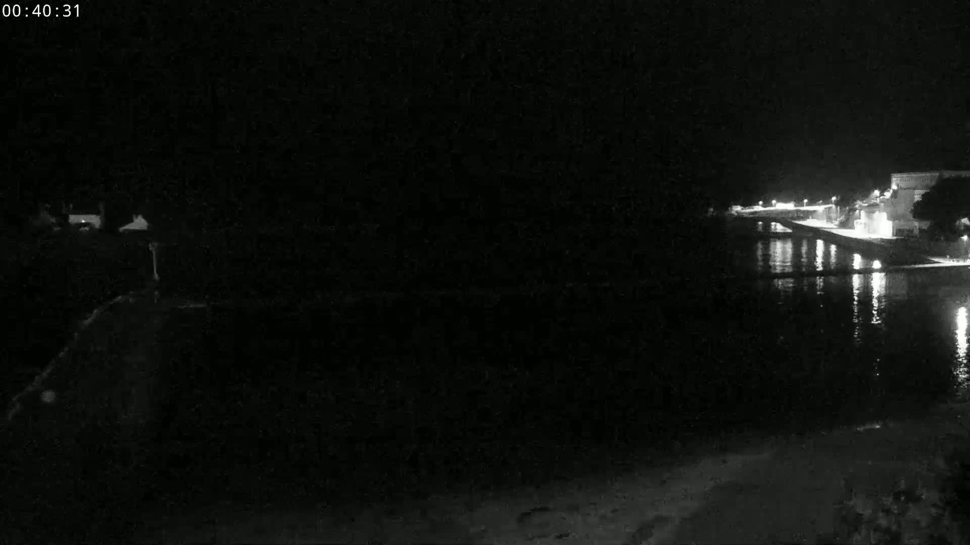 A nighttime view of a dark body of water reflecting lights from buildings along a shoreline.
