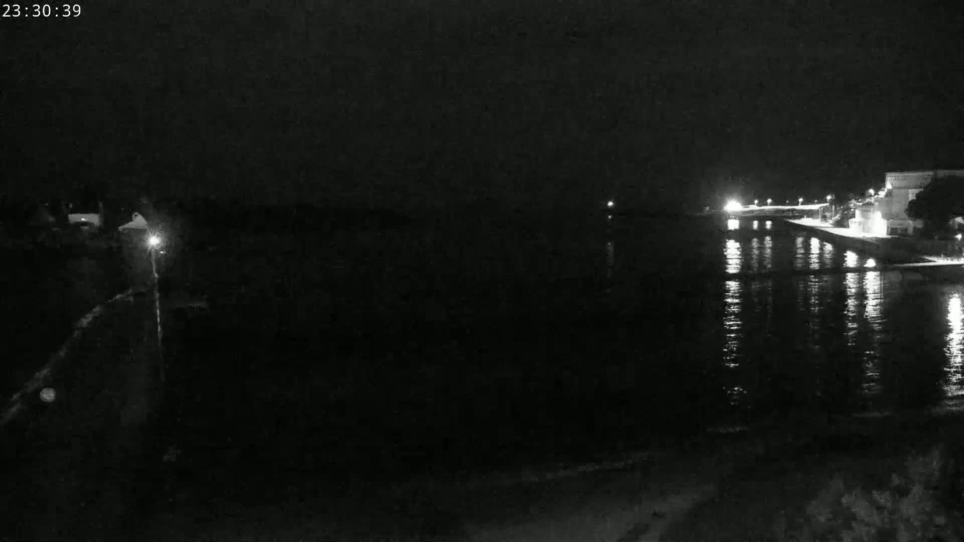A nighttime view of a calm body of water reflecting the lights of a waterfront area.