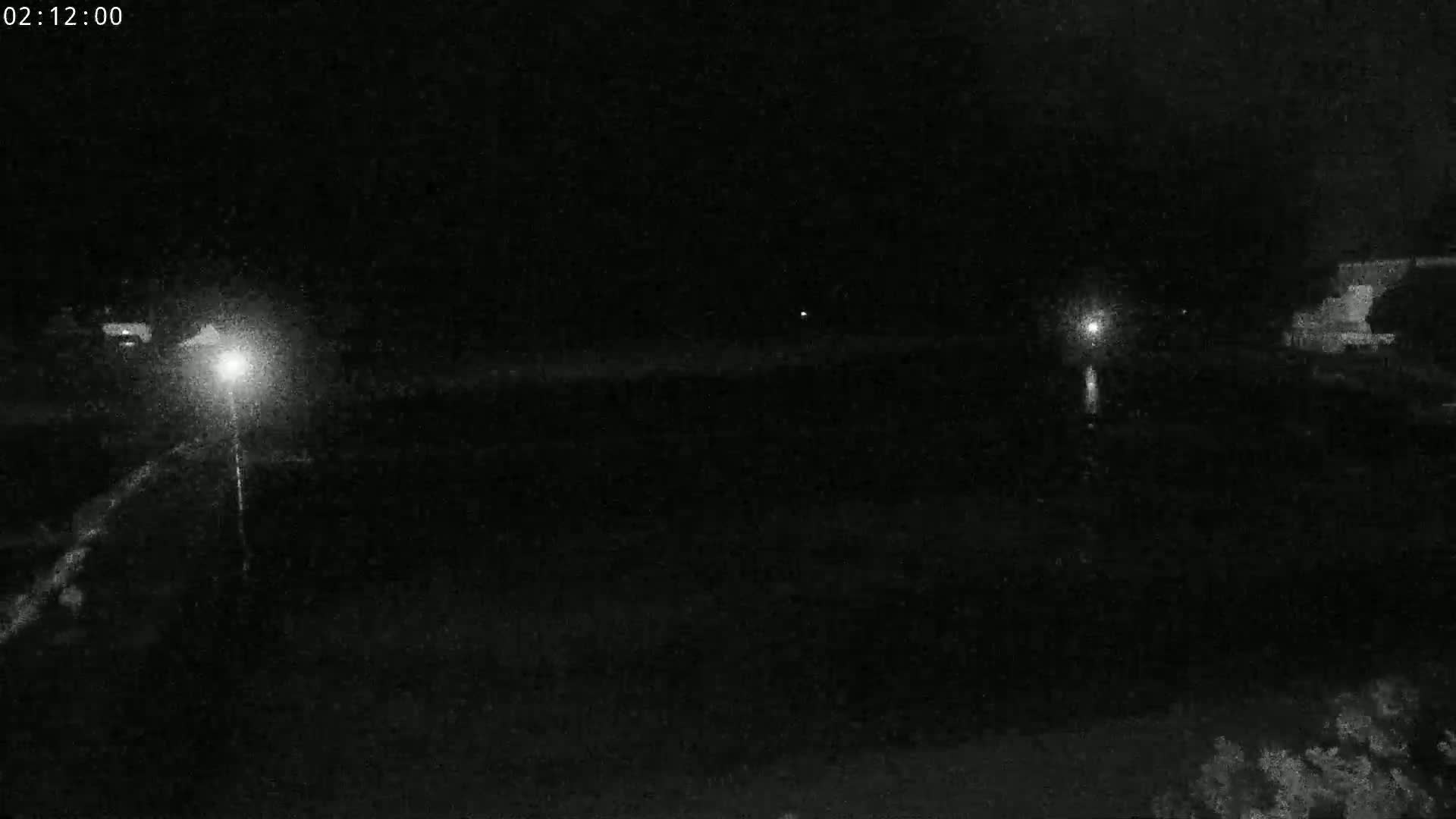 A nighttime, low-light view of a dark, possibly water-filled area with faint lights visible in the distance.