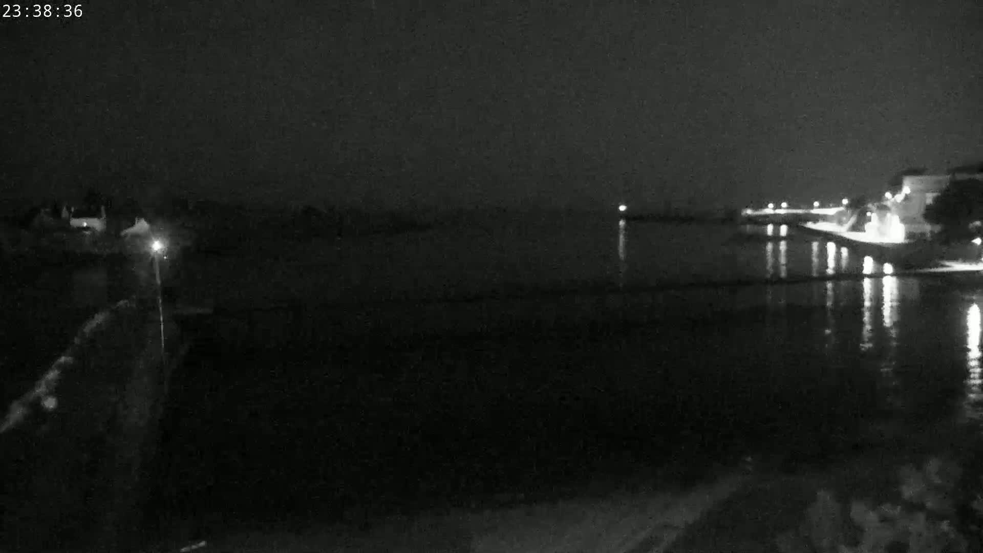 A nighttime view of a calm body of water reflecting lights from a shoreline with buildings.