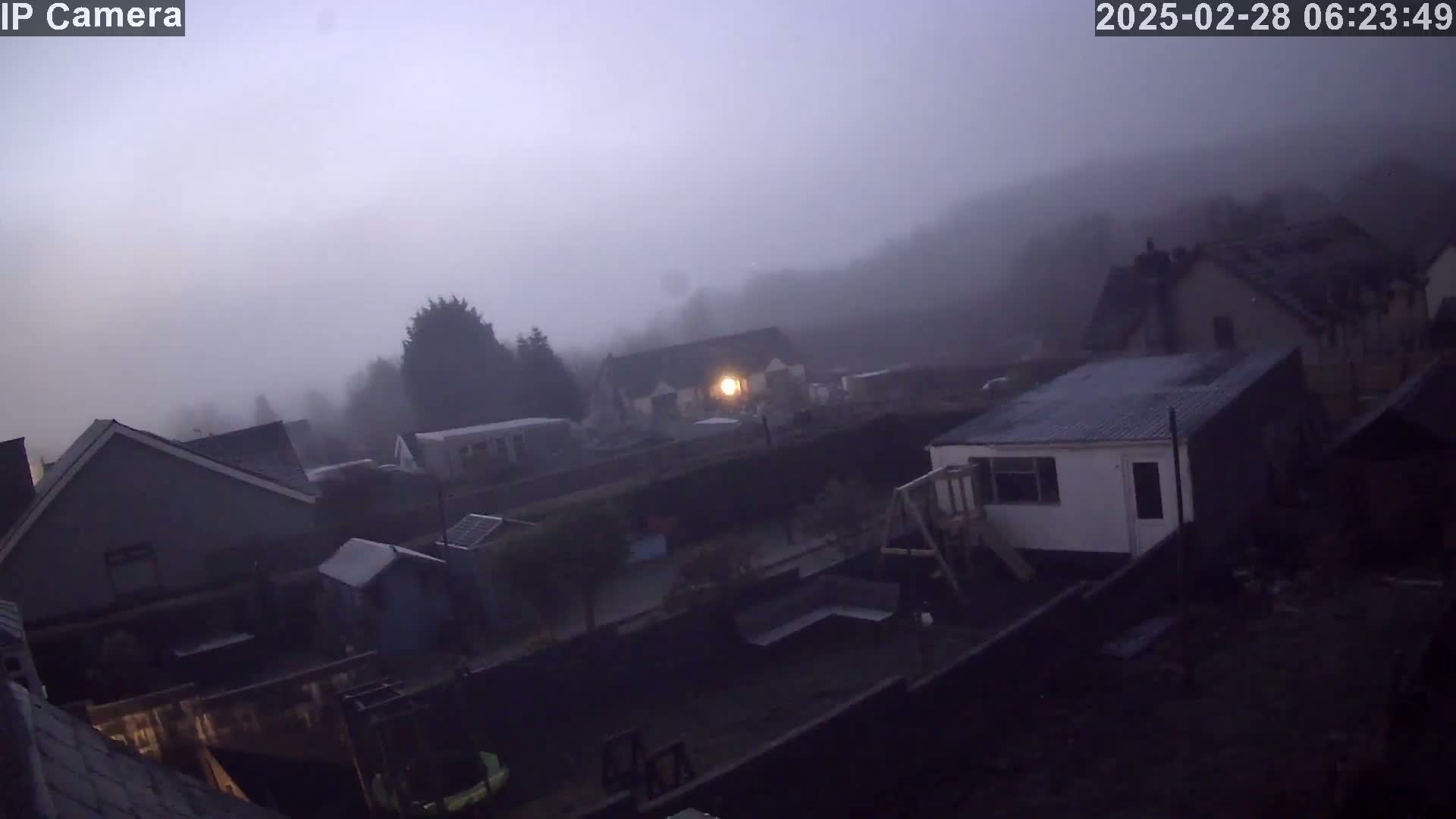 A foggy, early morning view of houses and backyards.