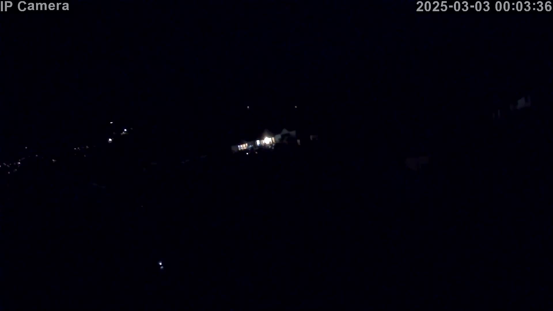 A dark, nighttime scene shows a few faint lights in the distance.