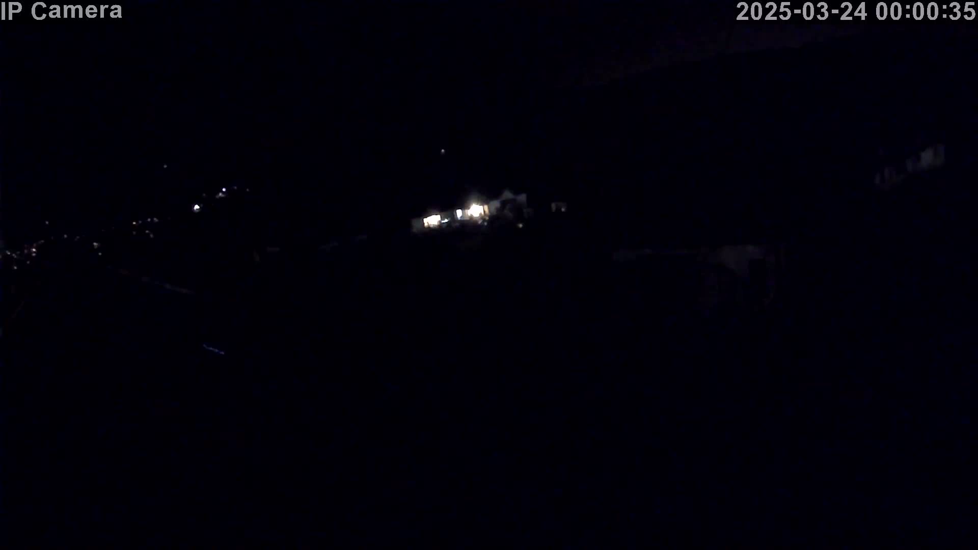 A nighttime, long-range view shows faintly lit buildings and possibly some distant lights in the darkness.