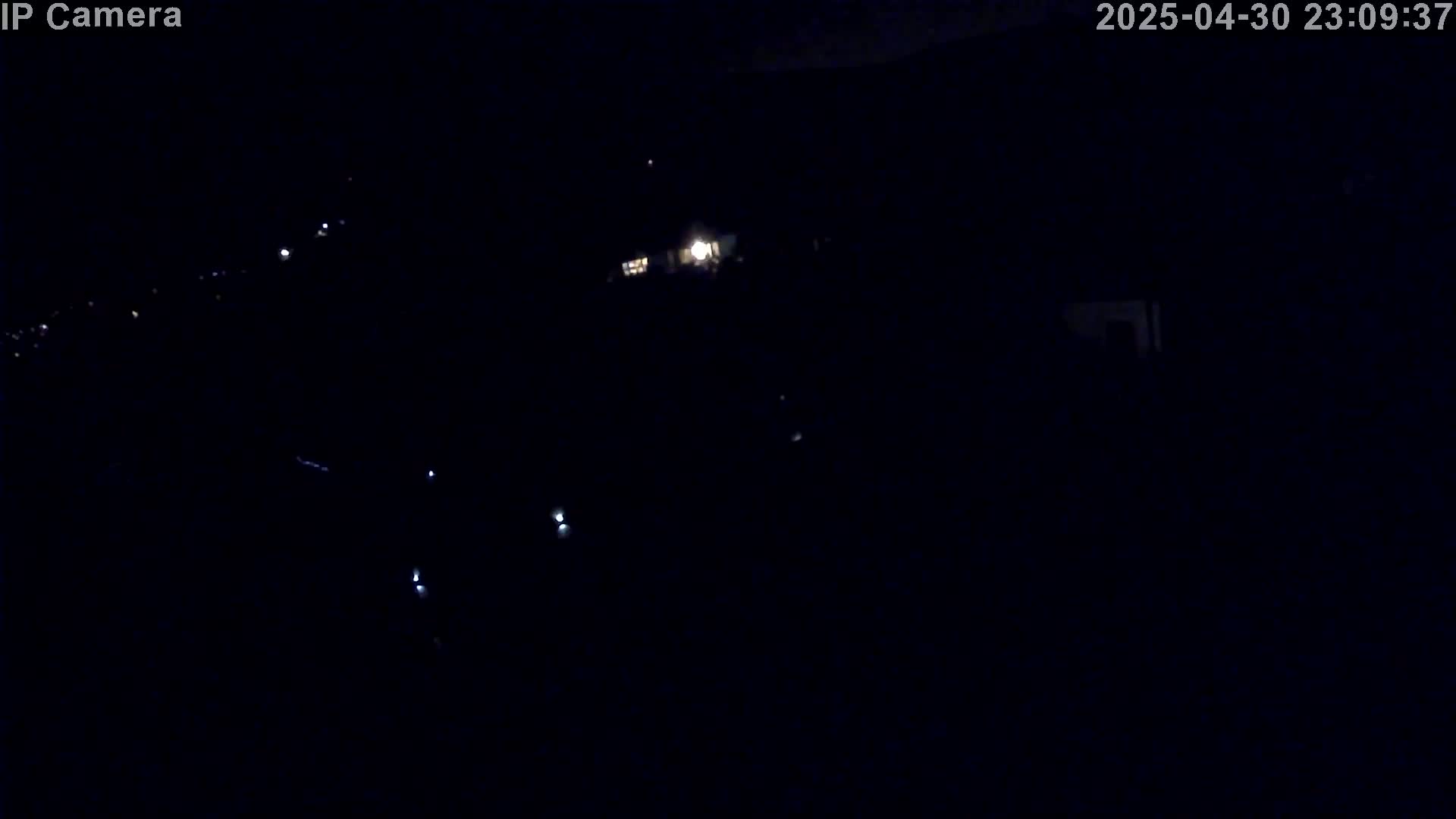 A dark, nighttime scene shows a few distant lights in the blackness.