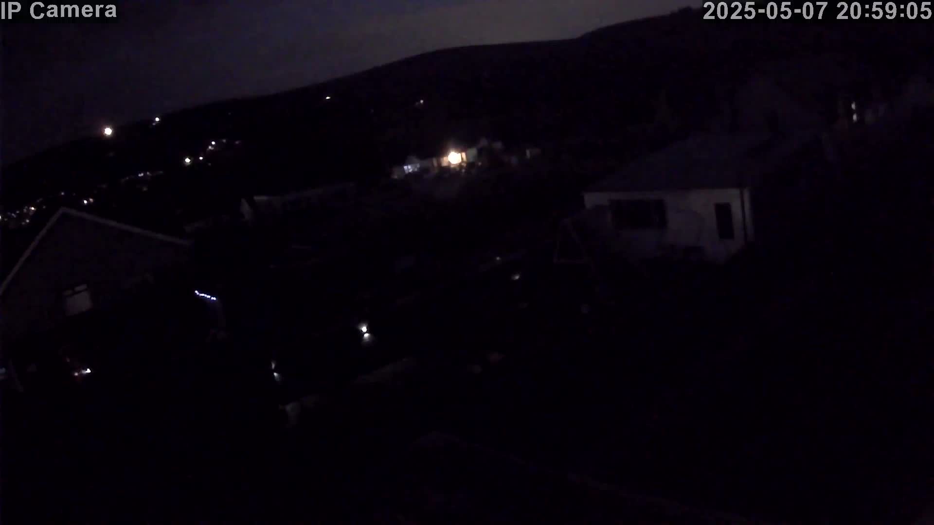 A nighttime, low-light view of houses and a hill under a dark sky.