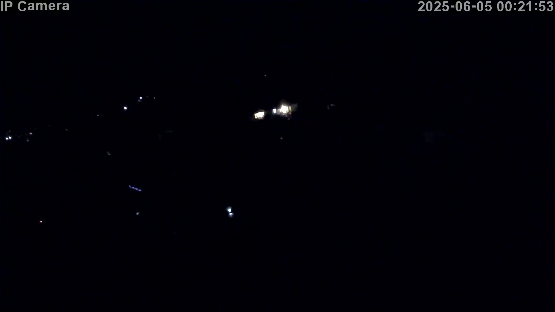 A nighttime, low-light outdoor scene shows a few distant, small lights in the darkness.