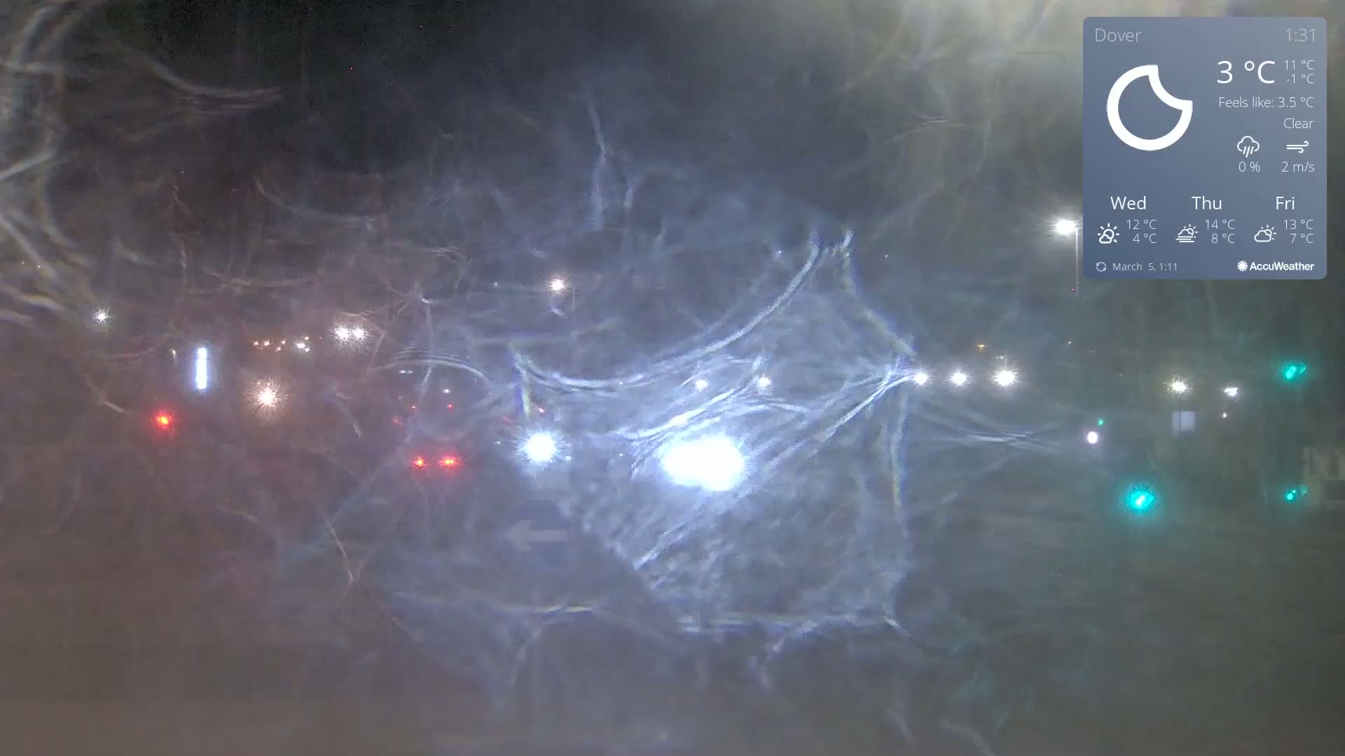A nighttime view of a road with blurry lights from vehicles in a clear, cold atmosphere.