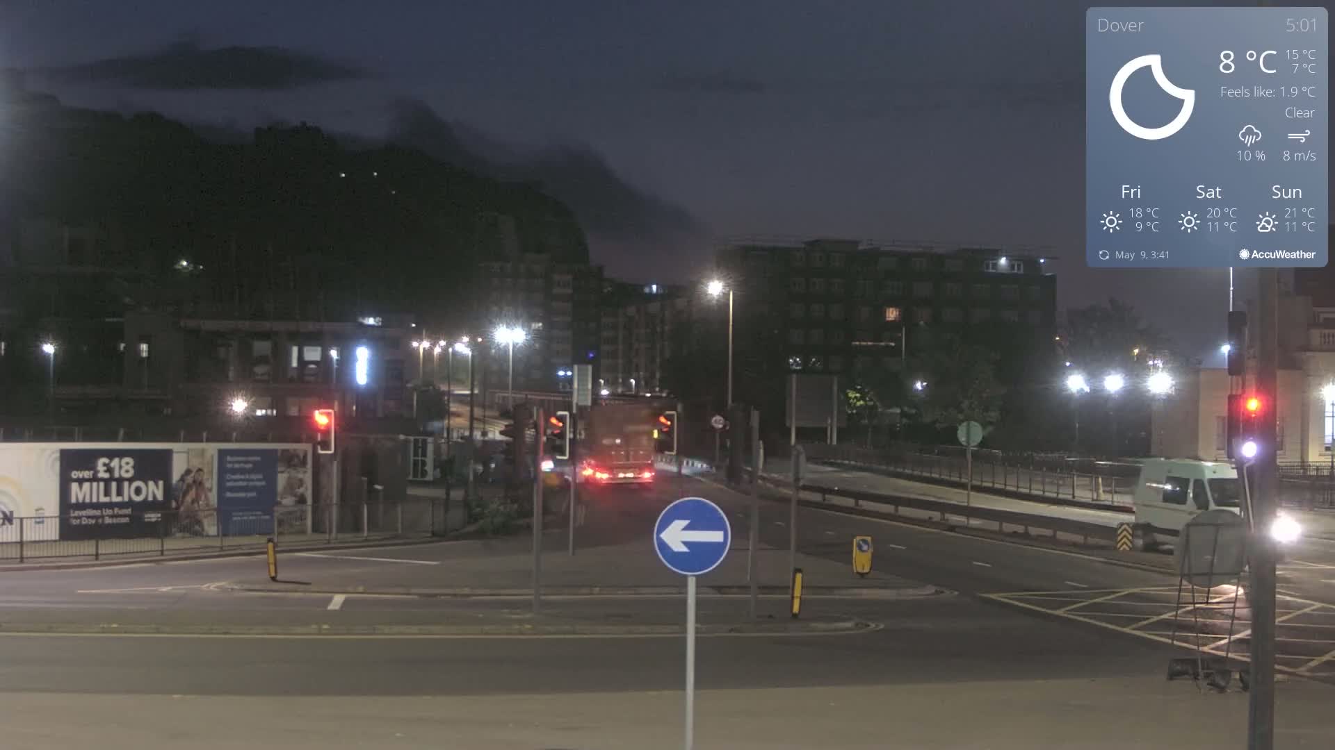 A nighttime street scene with a few vehicles, under a clear sky with a temperature of 8°C.