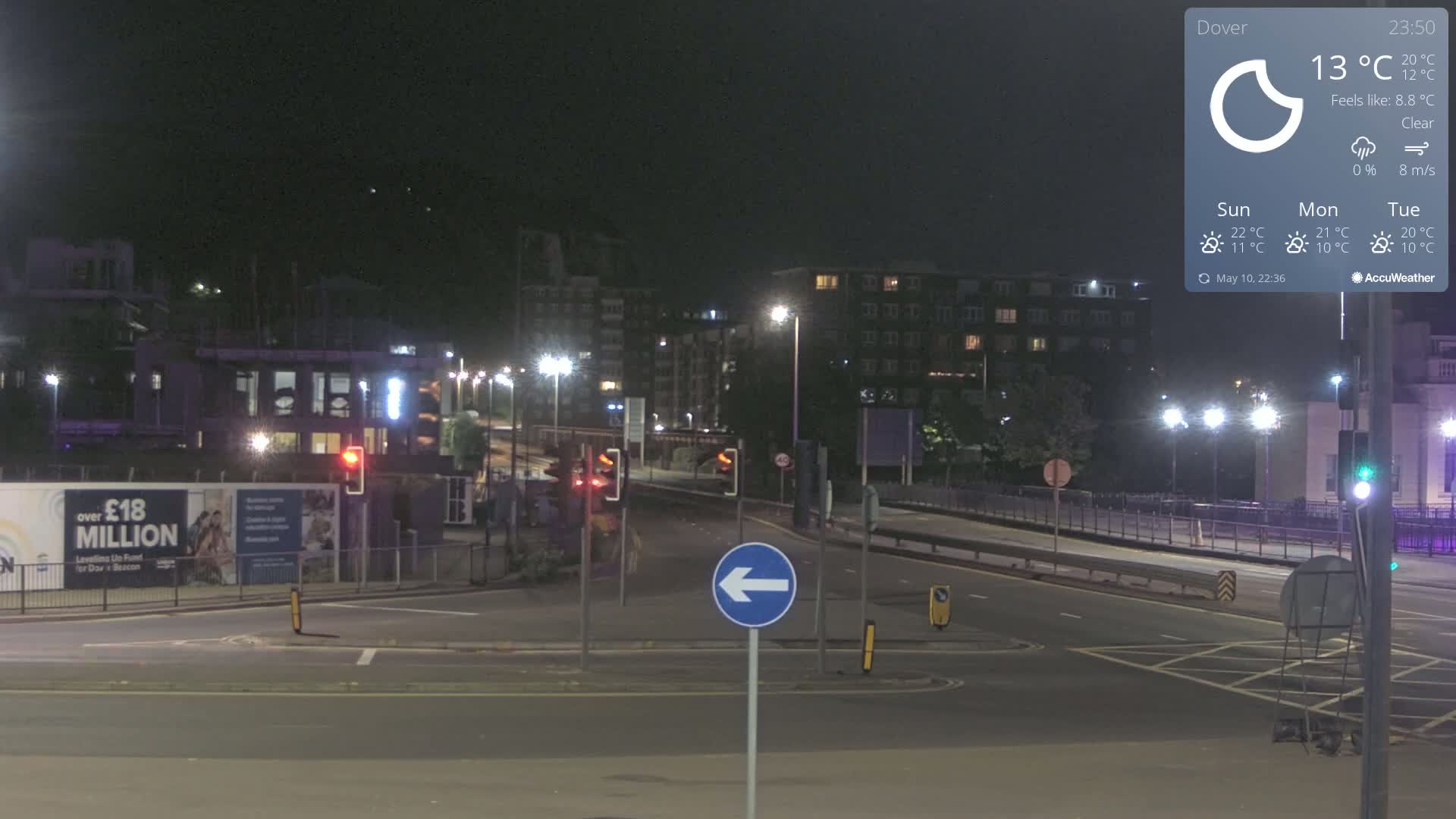 A nighttime, clear-weather view of a multi-lane road intersection in a city, with buildings and streetlights visible.