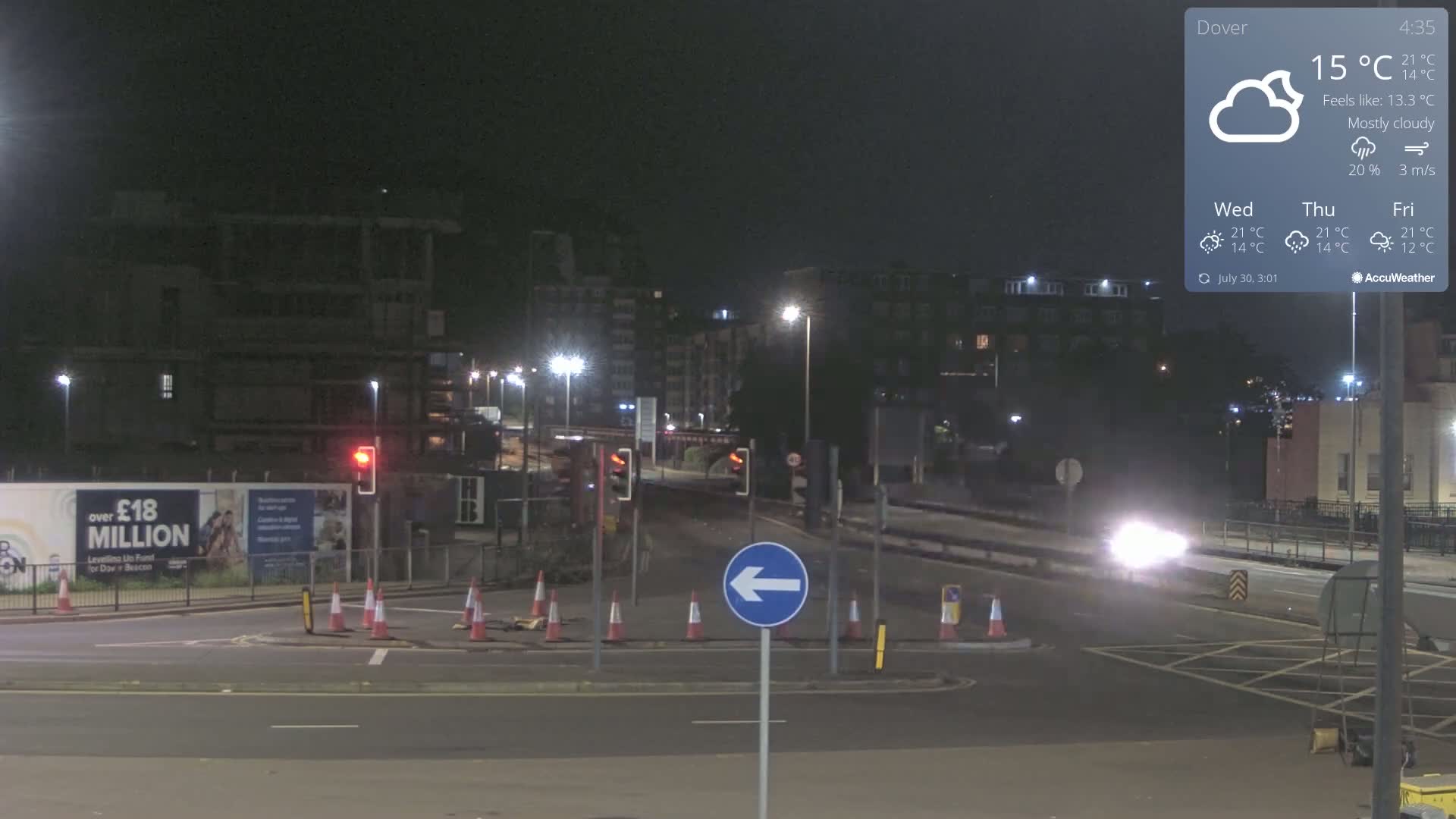A mostly cloudy, foggy road scene shows a multi-lane road with cars and a pedestrian, alongside a partially constructed building and traffic lights.