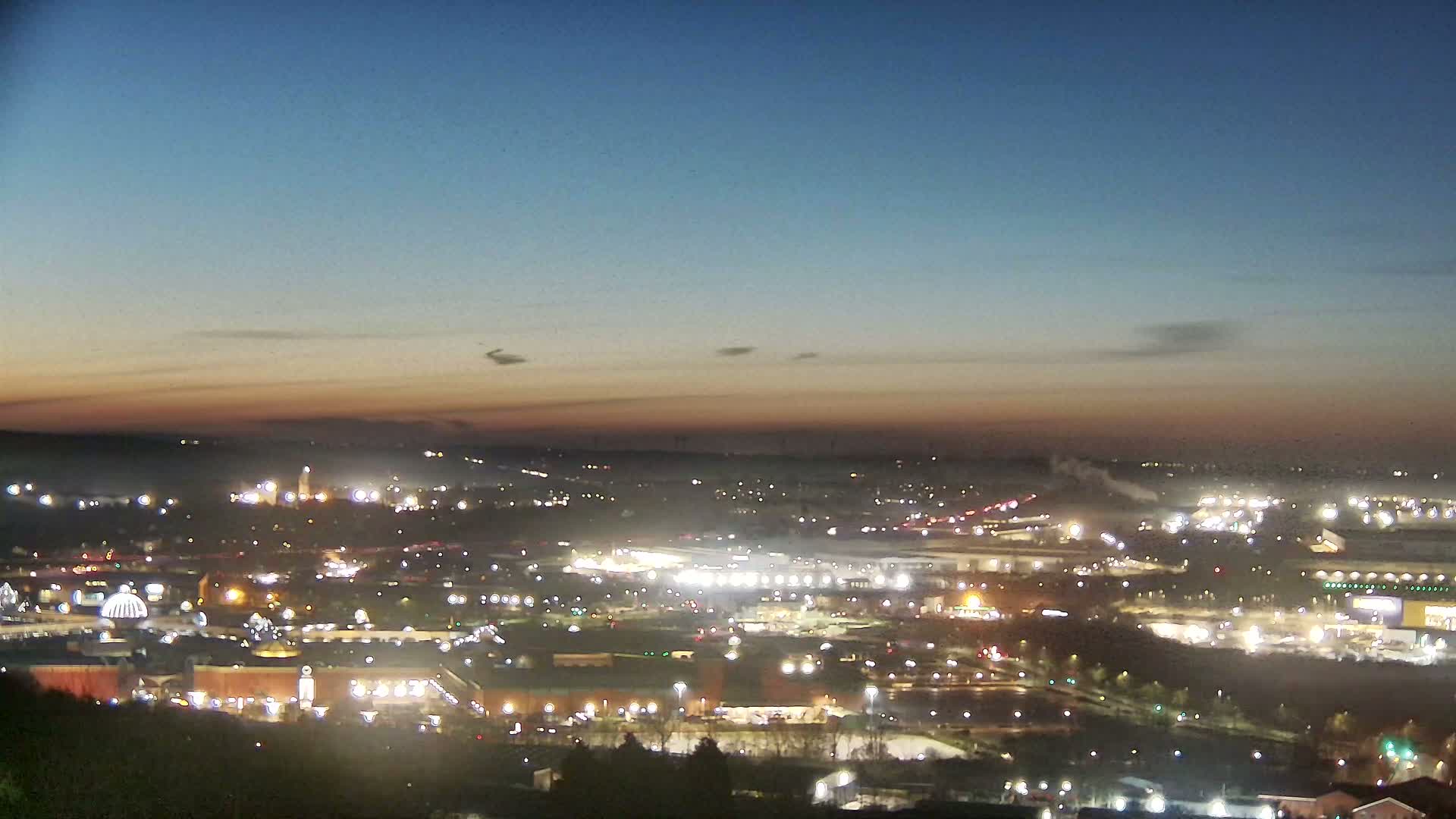 A sprawling city lights up at twilight under a clear, dusky sky.
