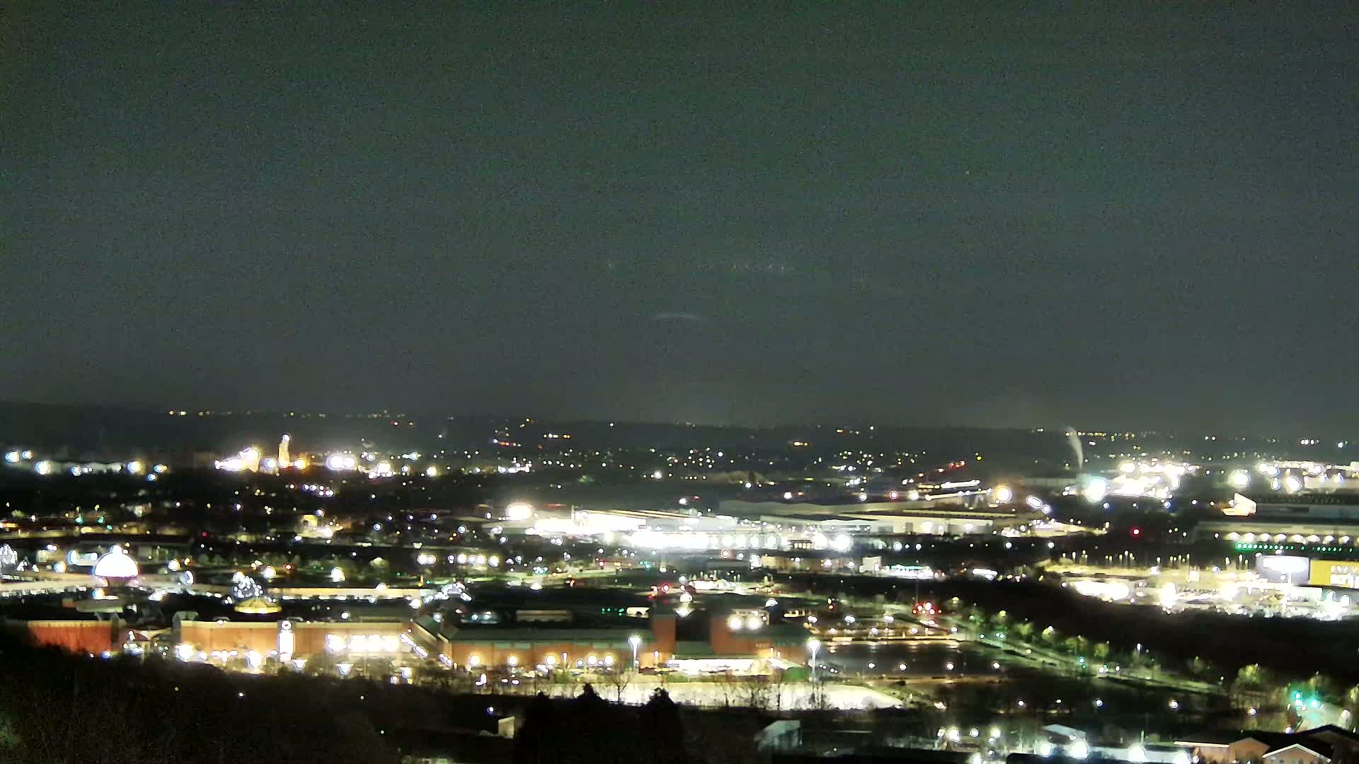 A nighttime, aerial view of a sprawling city illuminated by numerous lights under a dark, clear sky.