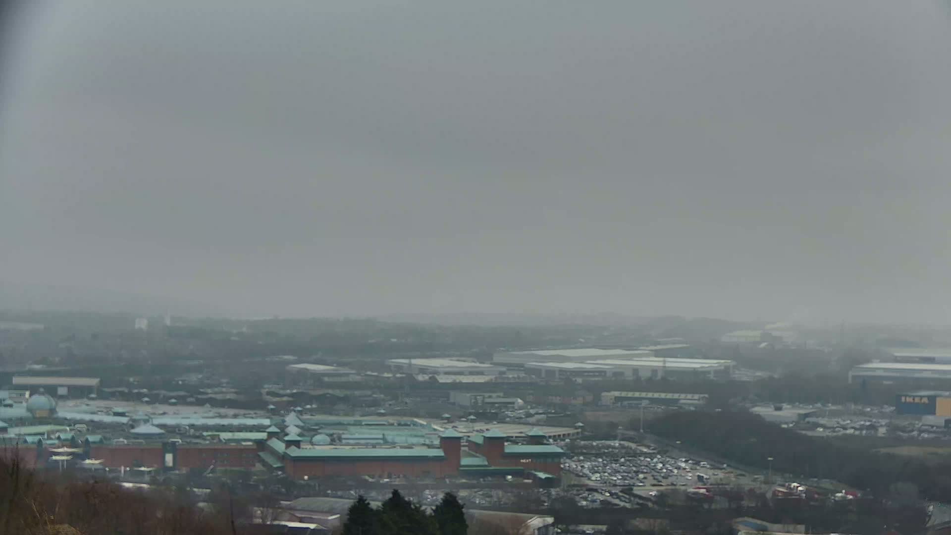 A hazy, overcast day reveals a sprawling cityscape view, featuring a large shopping center and surrounding industrial areas.