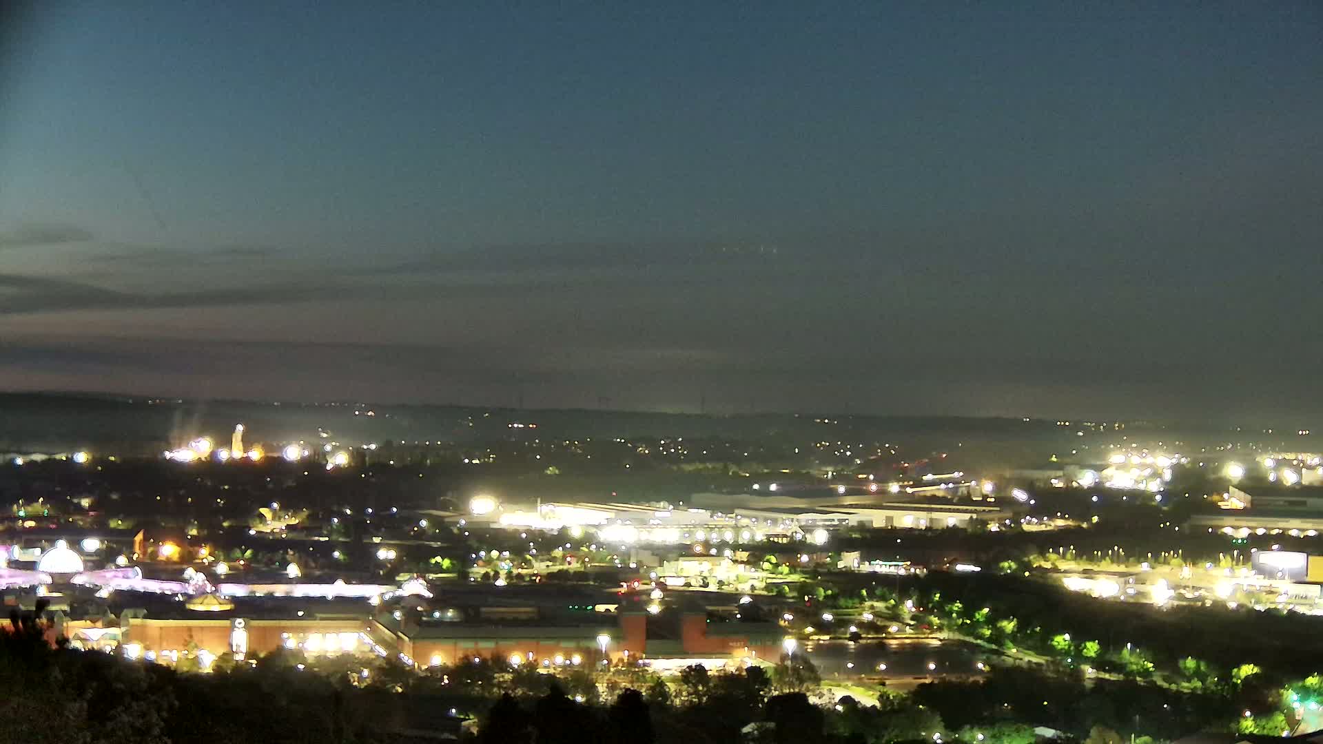 A nighttime view of a city with many illuminated buildings and structures under a clear, dark sky.