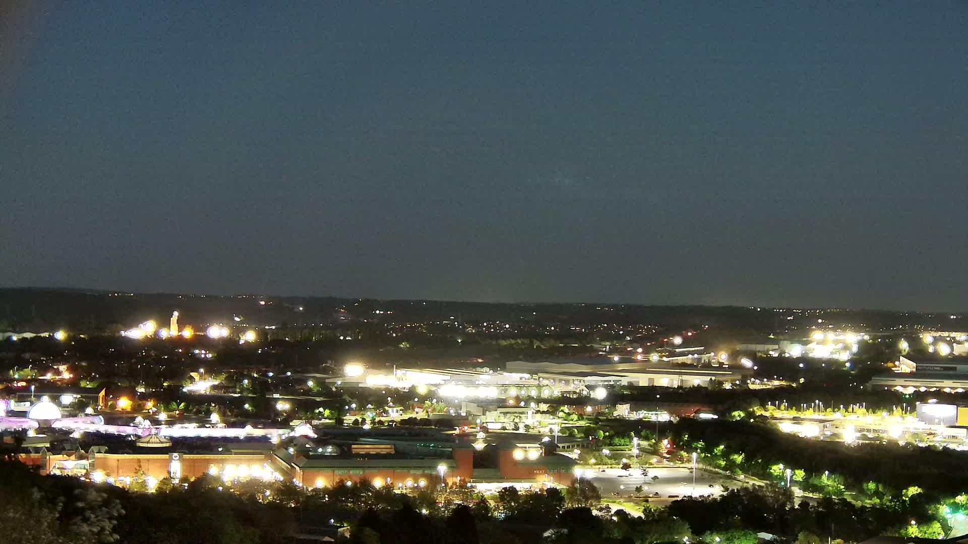 A nighttime, high-angle view of a sprawling city illuminated by artificial lights, under a clear, dark sky.